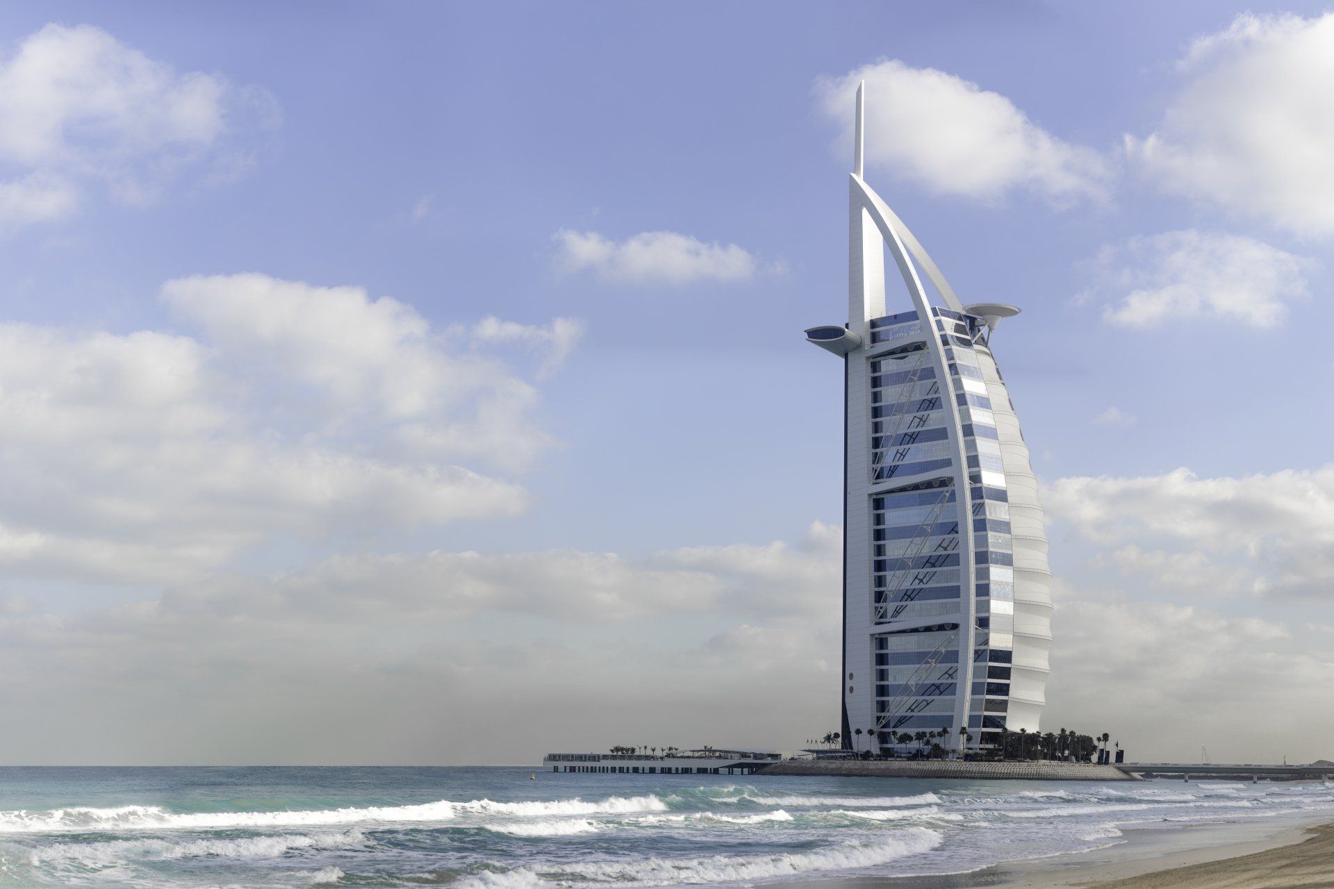 A large white building sits on a beach near the ocean
