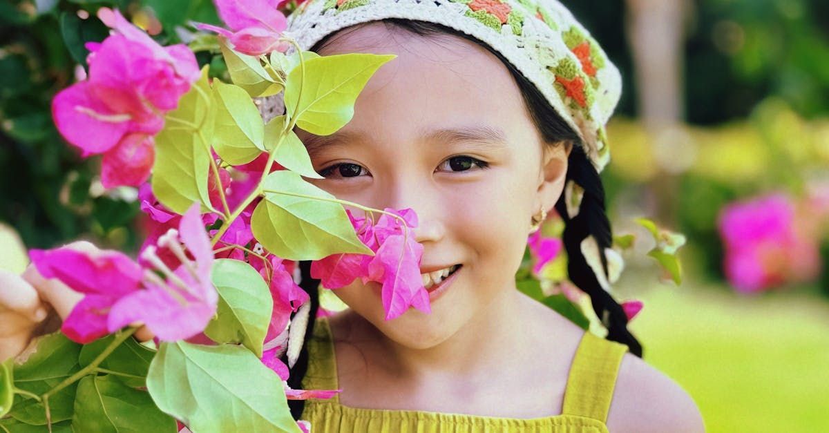 A little girl is holding purple flowers in front of her face.