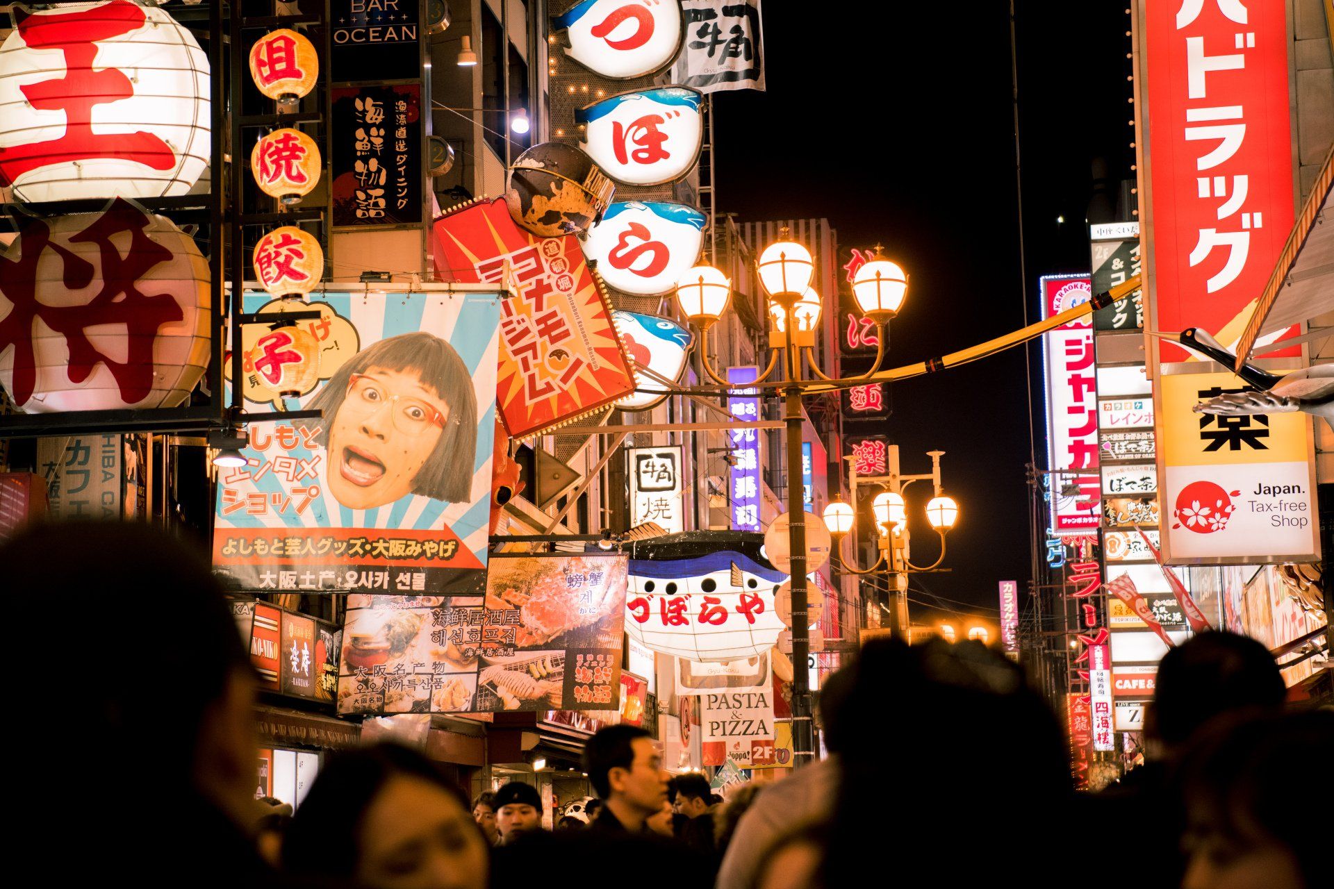 A crowd of people are walking down a busy street at night.
