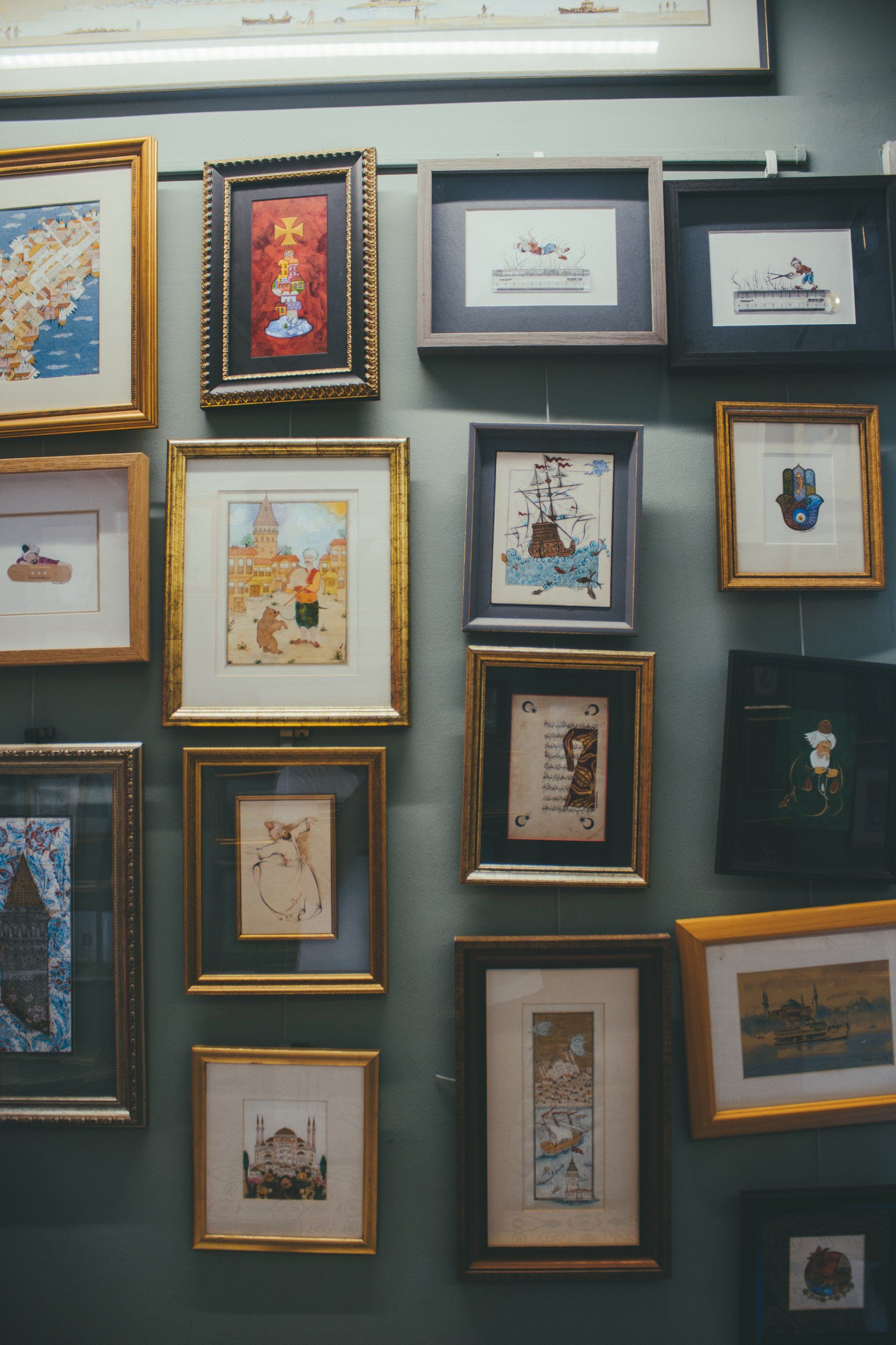 A wall filled with lots of framed pictures on it.