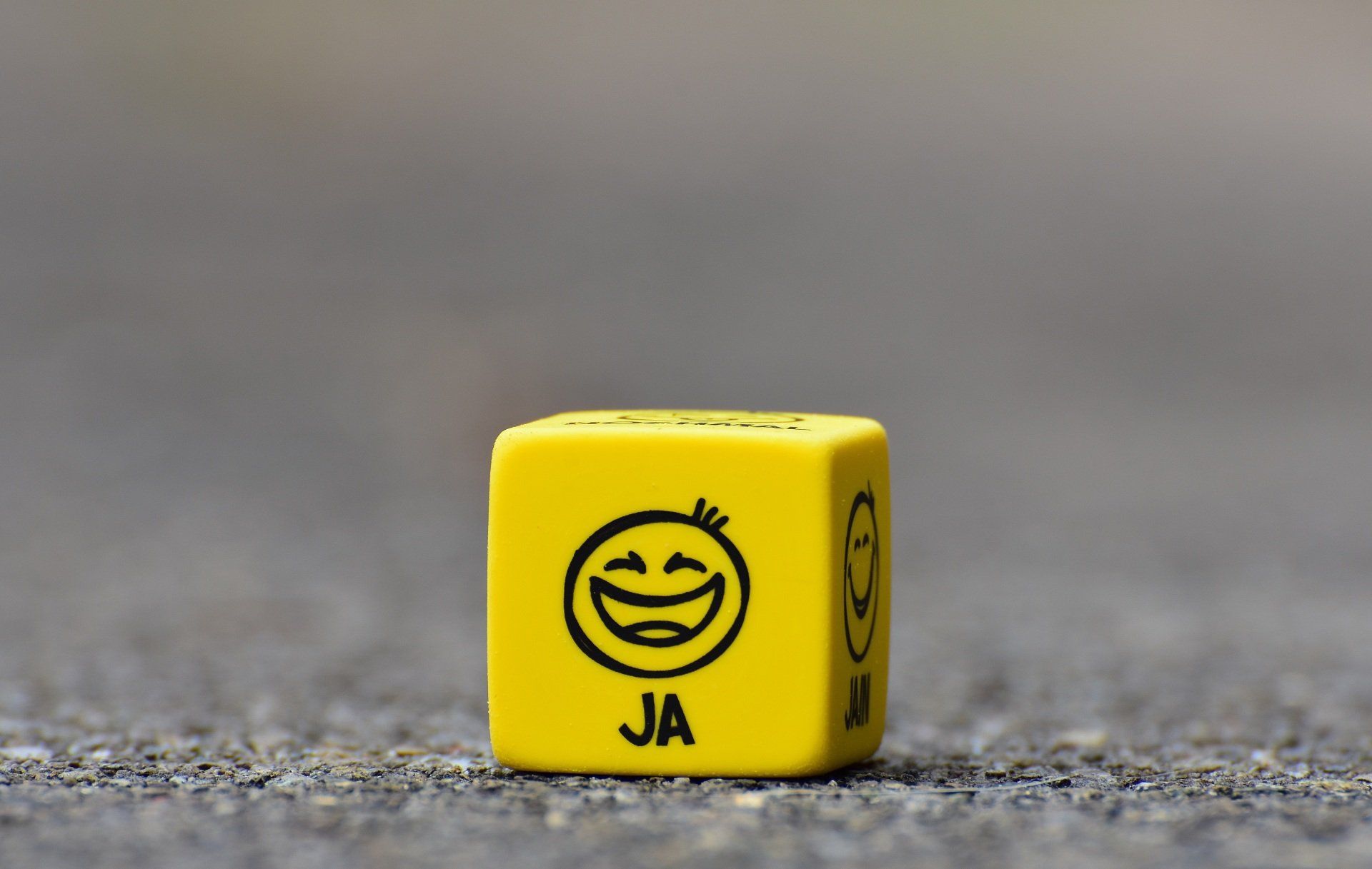 Yellow die with a smiling face and the word 