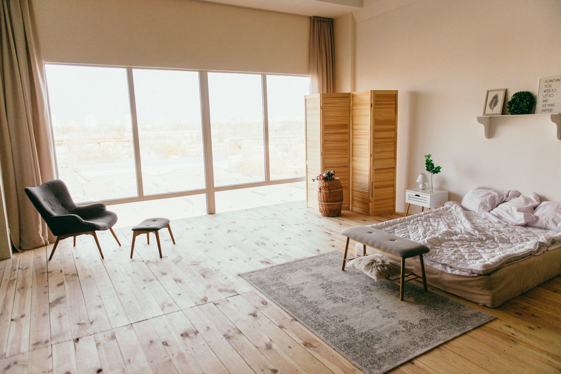 a bedroom with a bed , chair , rug and large windows .
