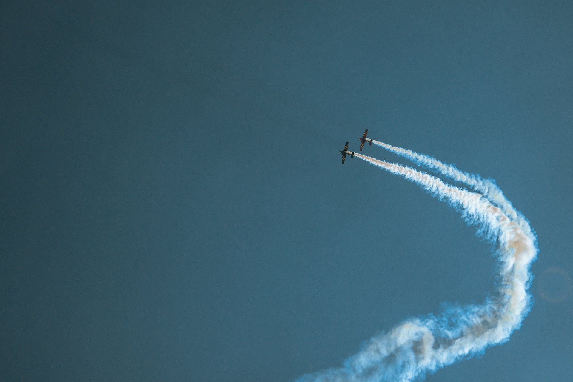 Two airplanes are flying in the sky with smoke trails behind them.
