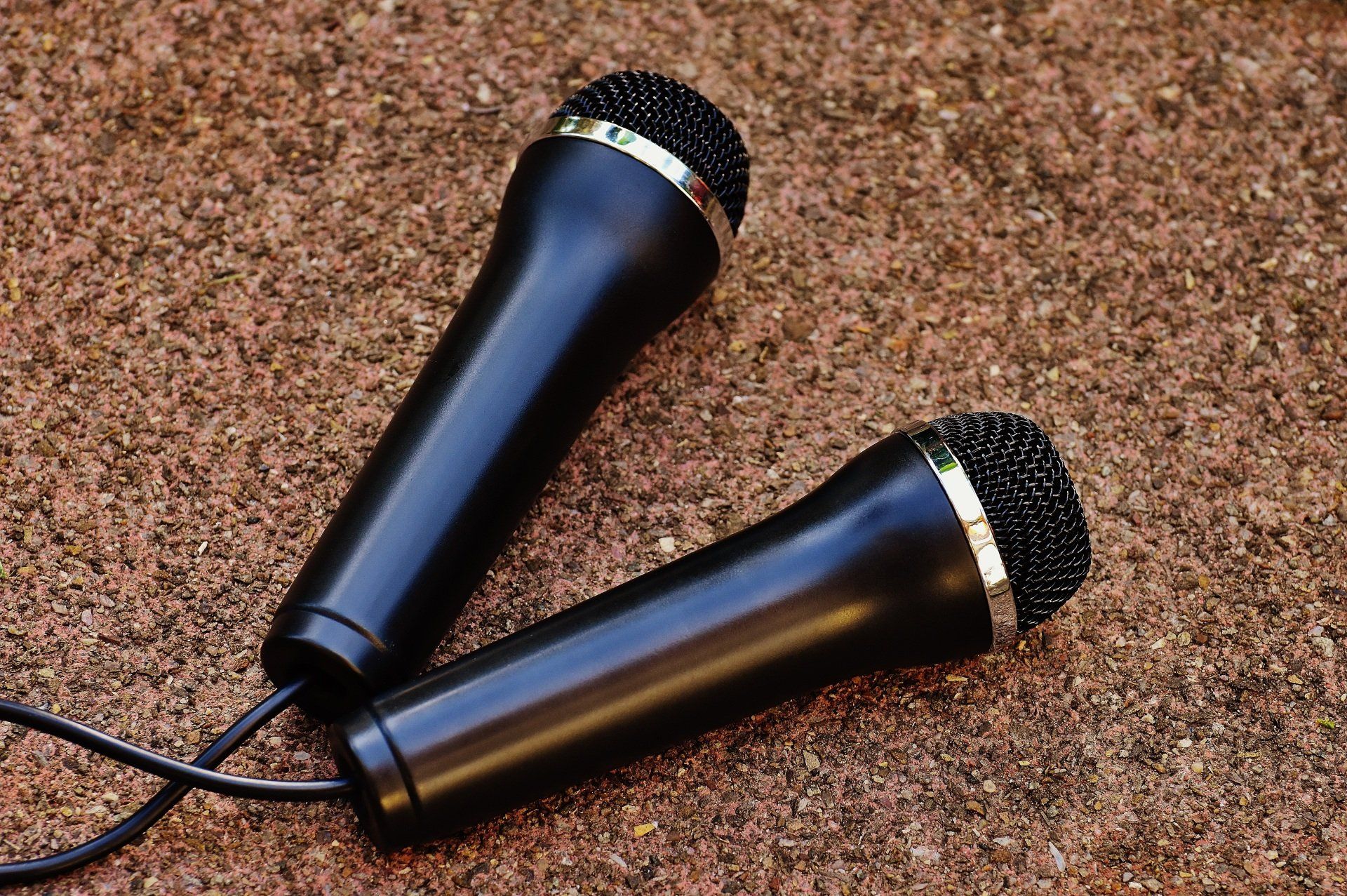 Two black microphones are laying on a brown surface