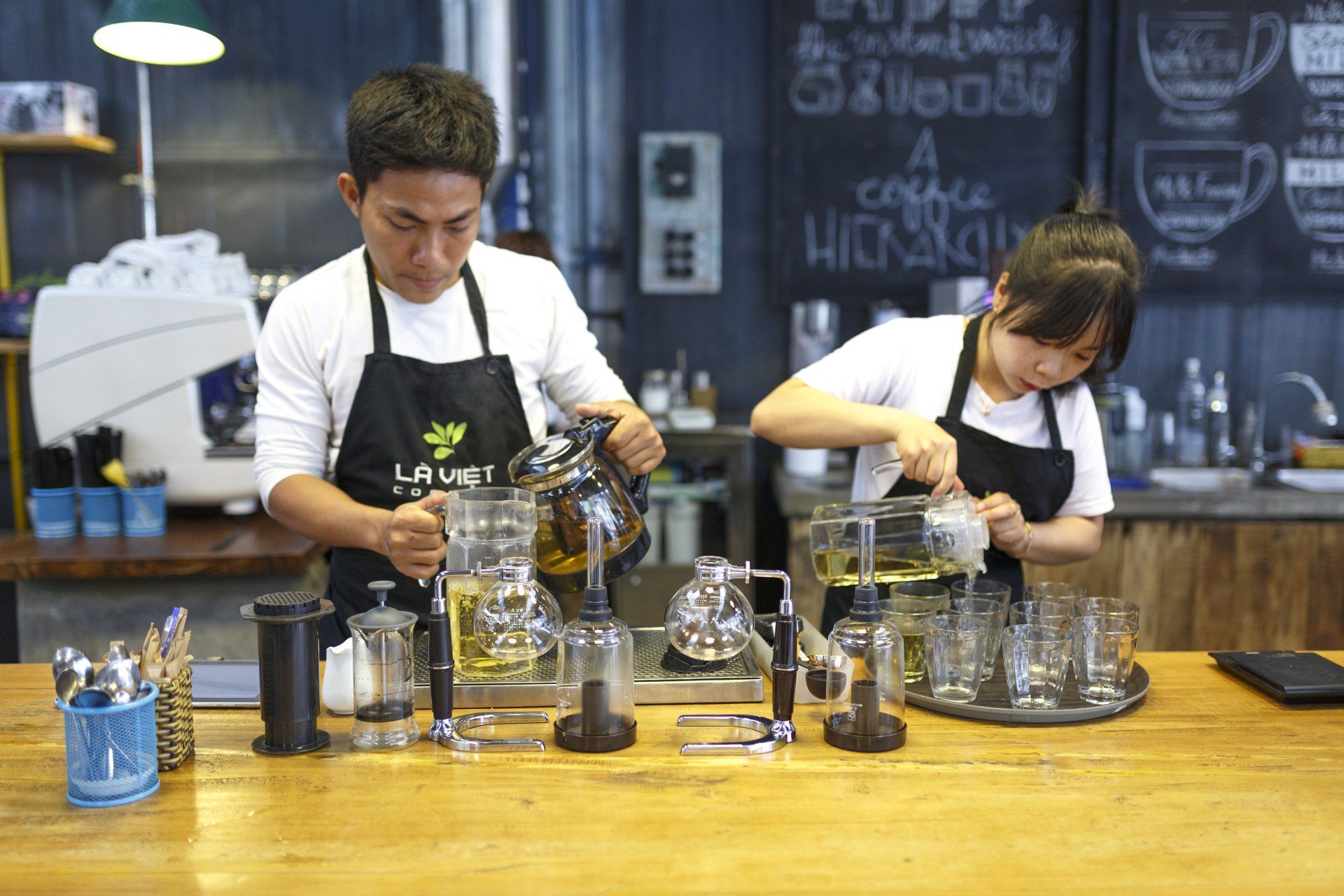 A man and a woman are preparing coffee in a cafe.