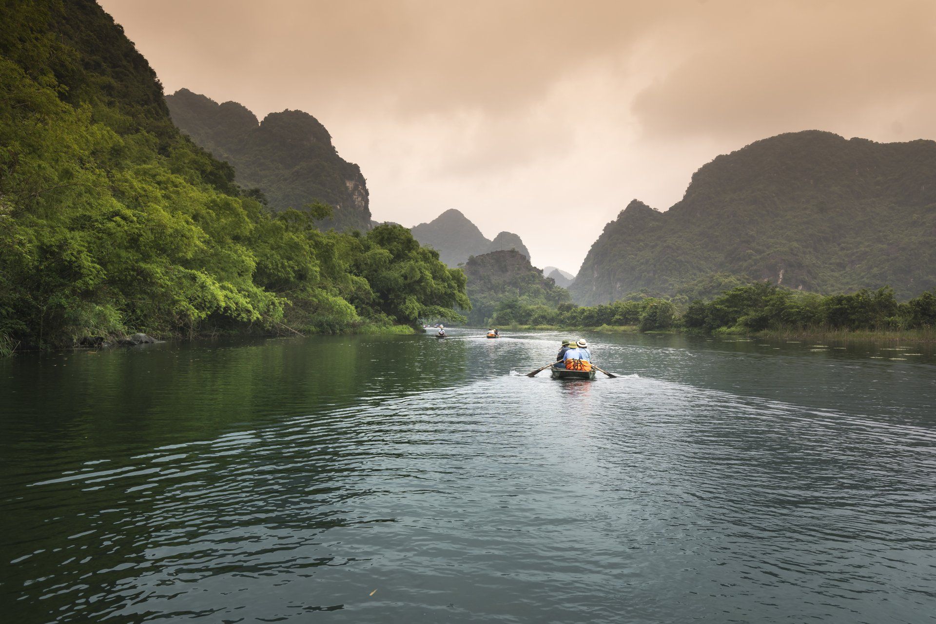 a boat is floating down a Costa Rican river with mountains in the background .