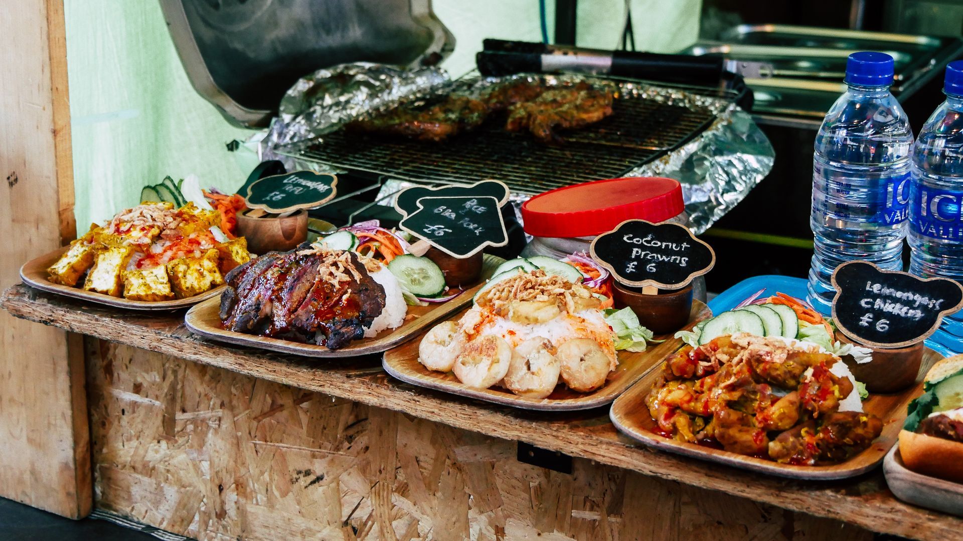 A wooden table topped with plates of food and water bottles.