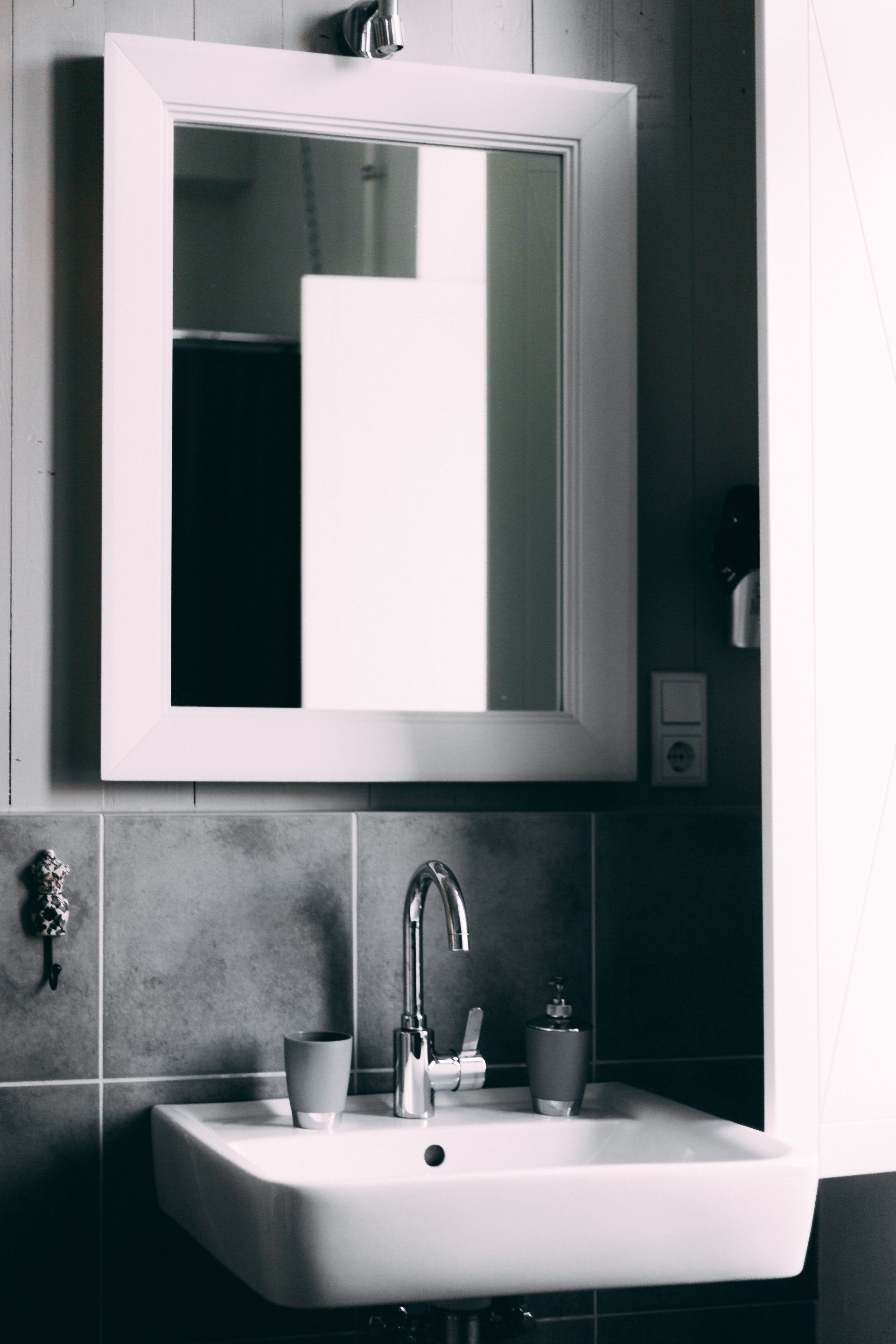 White bathroom sink and mirror on tiled wall.