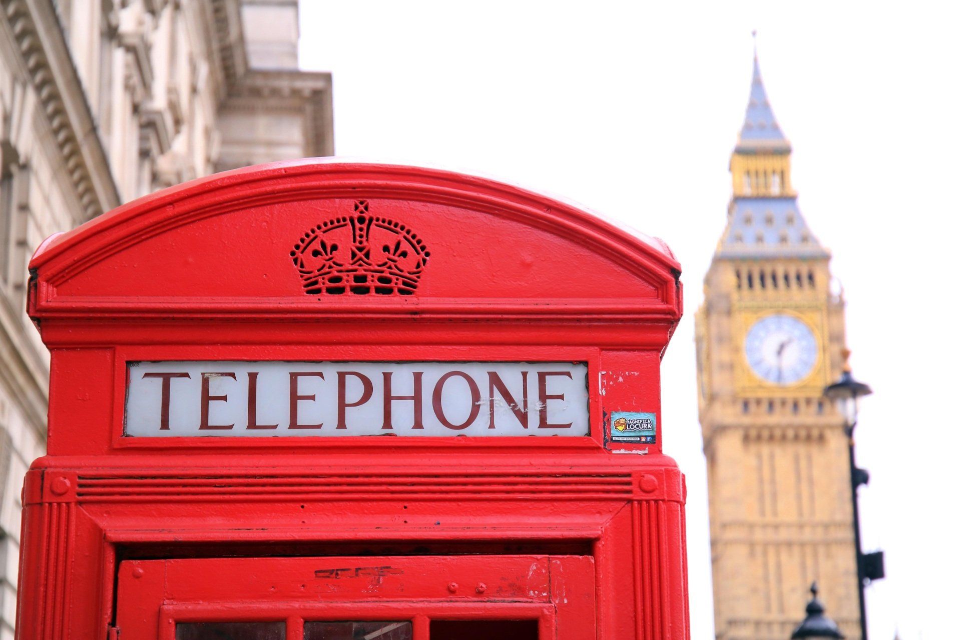 Rote Telefonzelle in London mit Big Ben im Hintergrund.