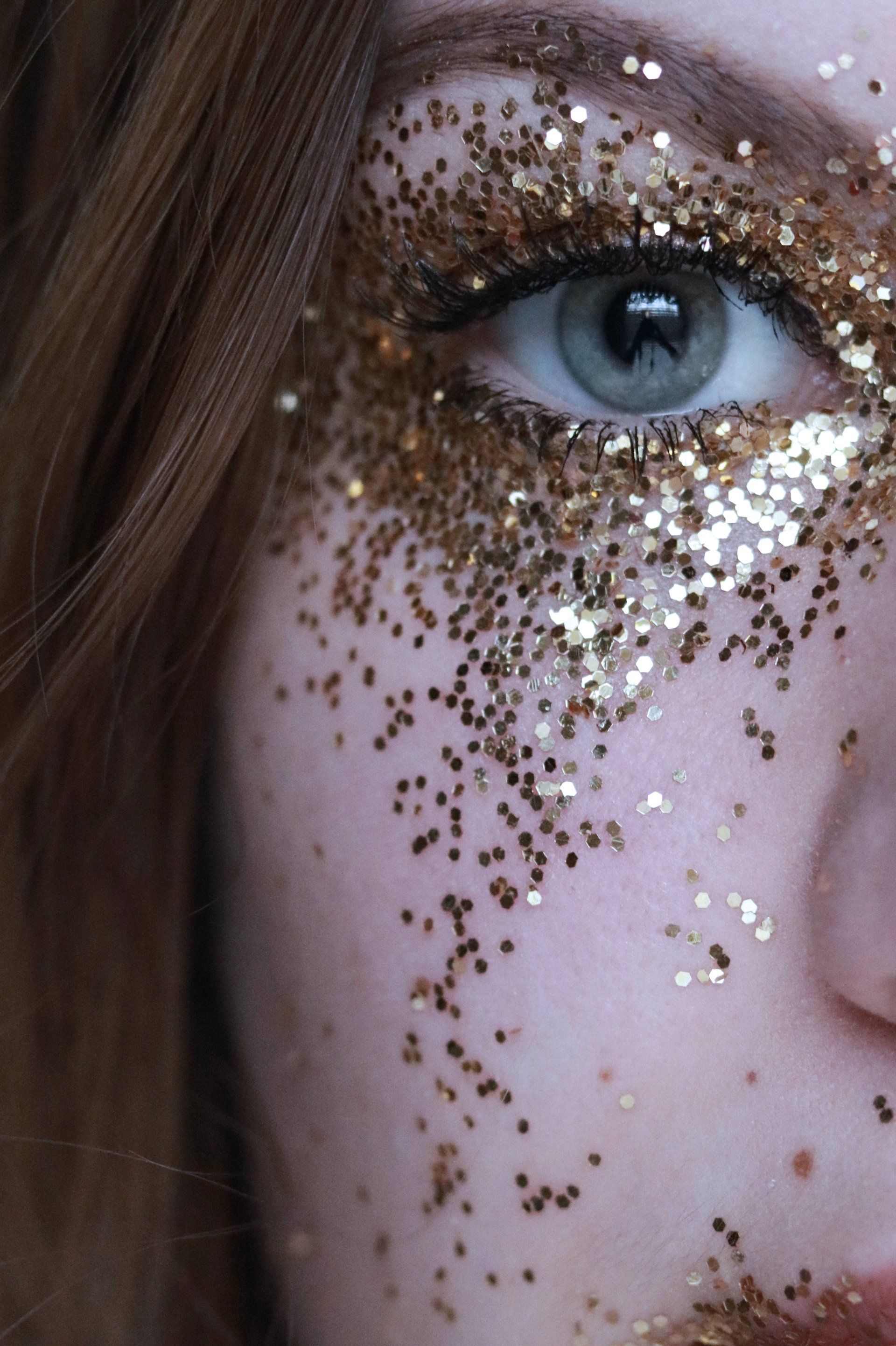 Een close-up van het gezicht van een vrouw met gouden glitters erop