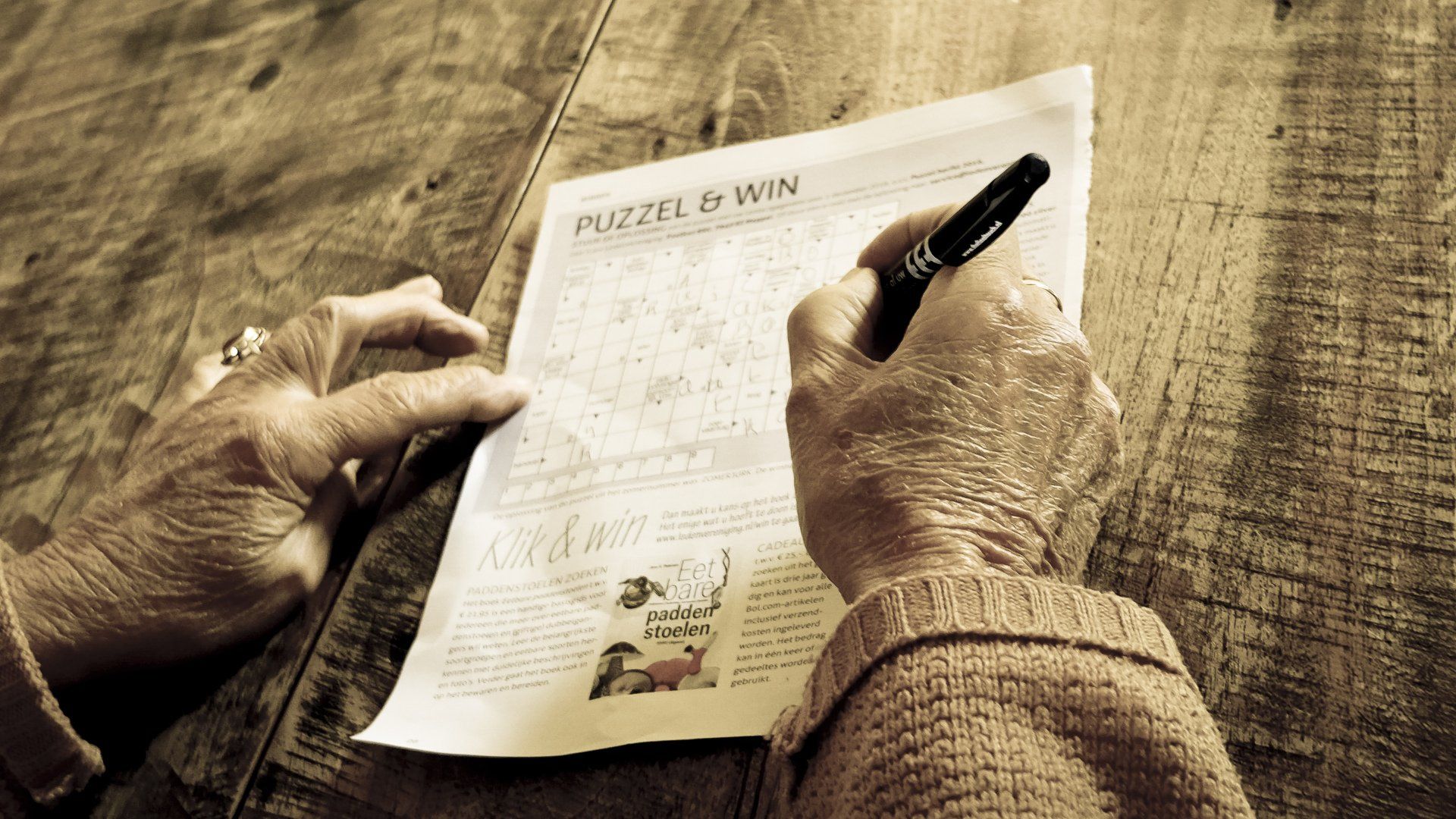 A person is writing on a piece of paper that says puzzle to win