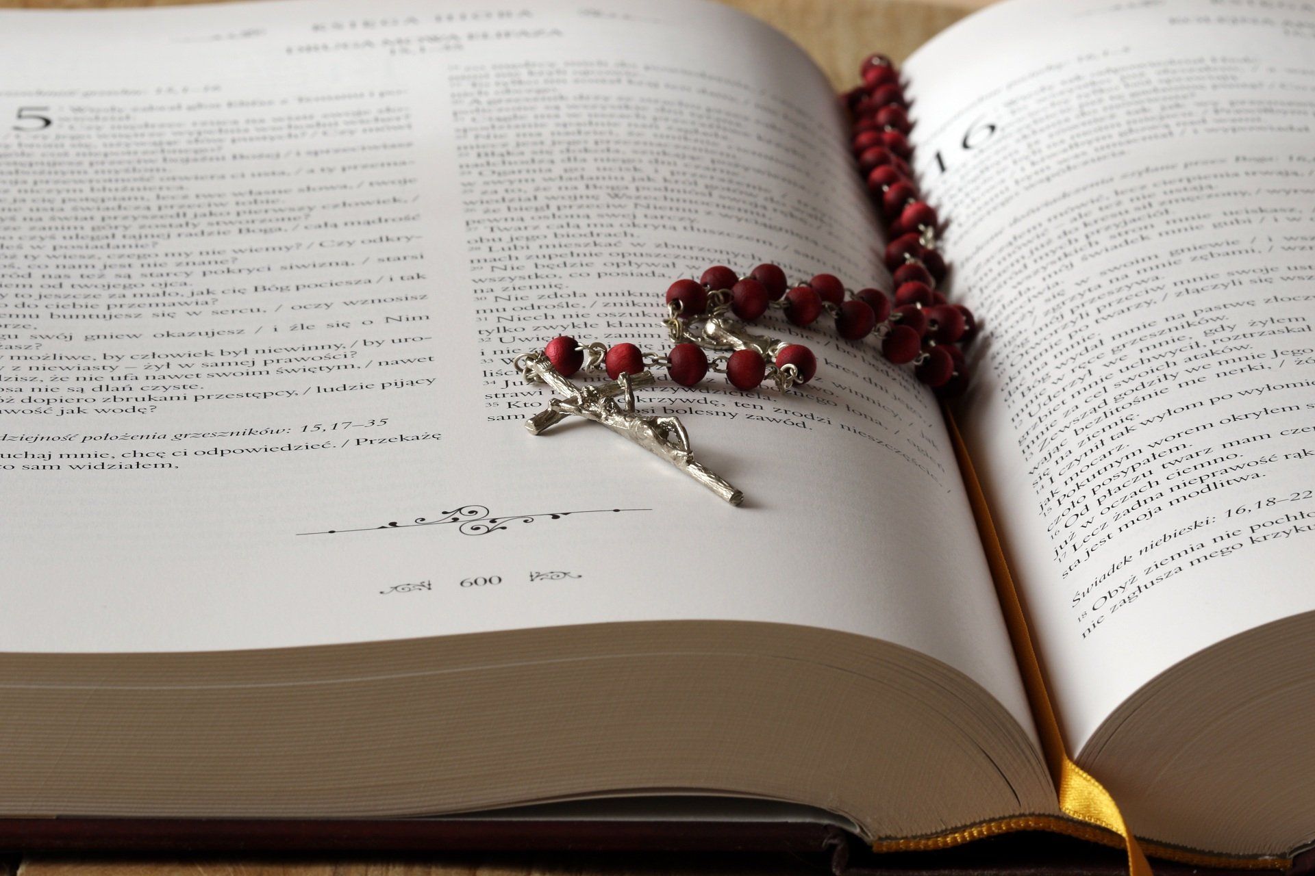 A rosary is sitting on top of an open bible.
