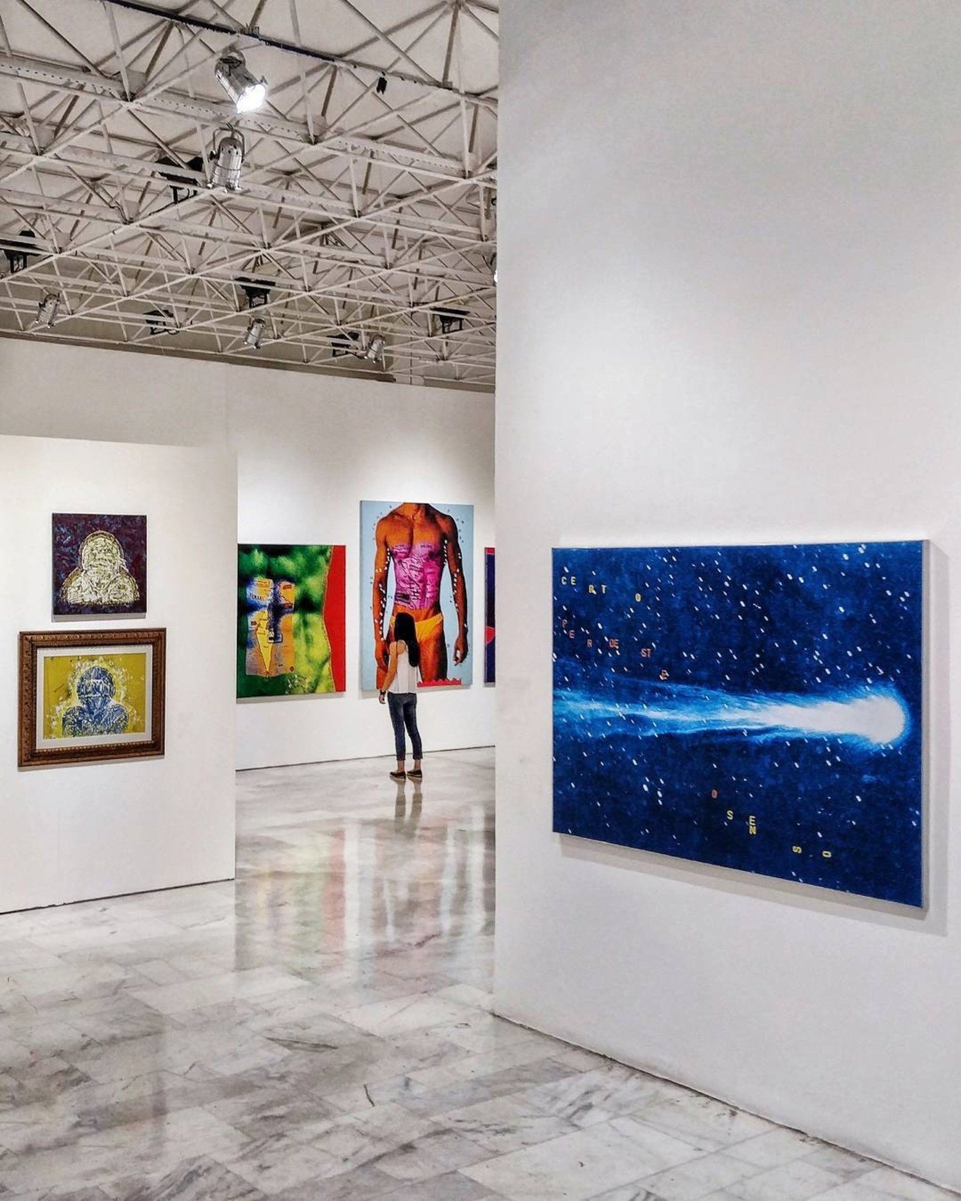 A woman is looking at a painting in a museum