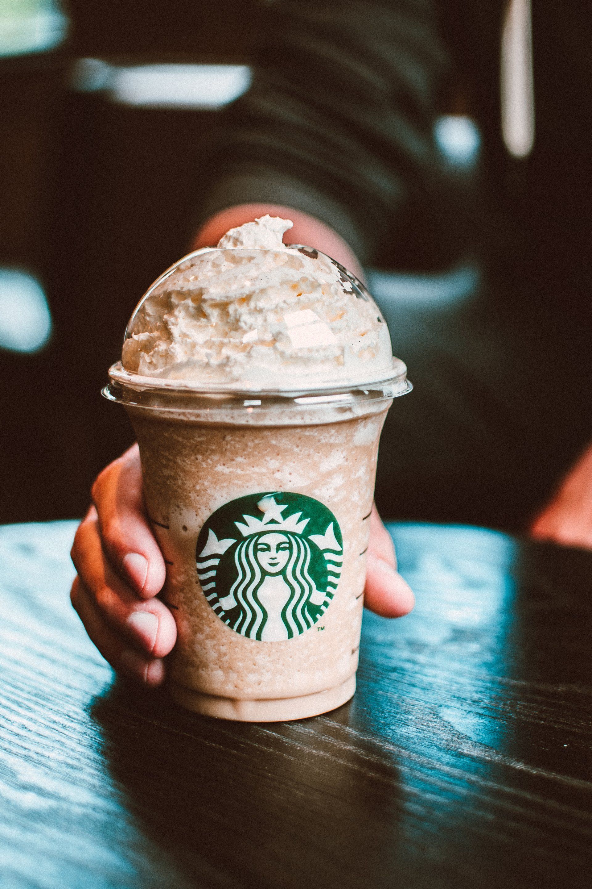 A person is holding a starbucks drink in their hand