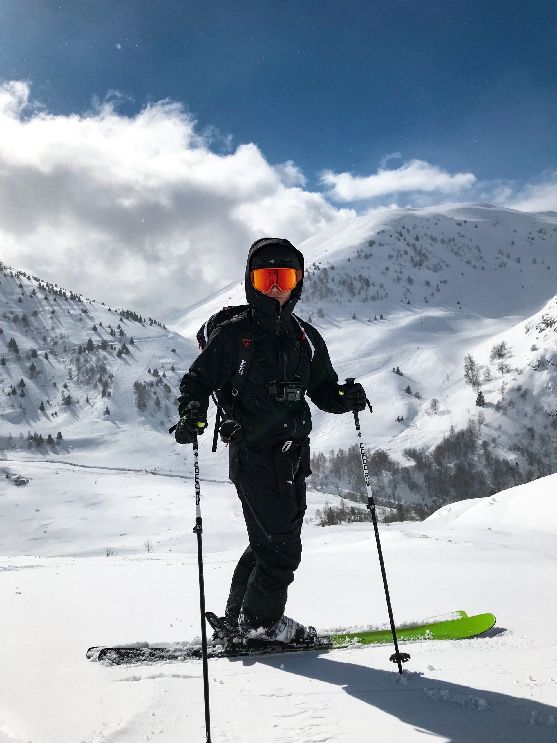 a person is standing on skis on top of a snow covered mountain .