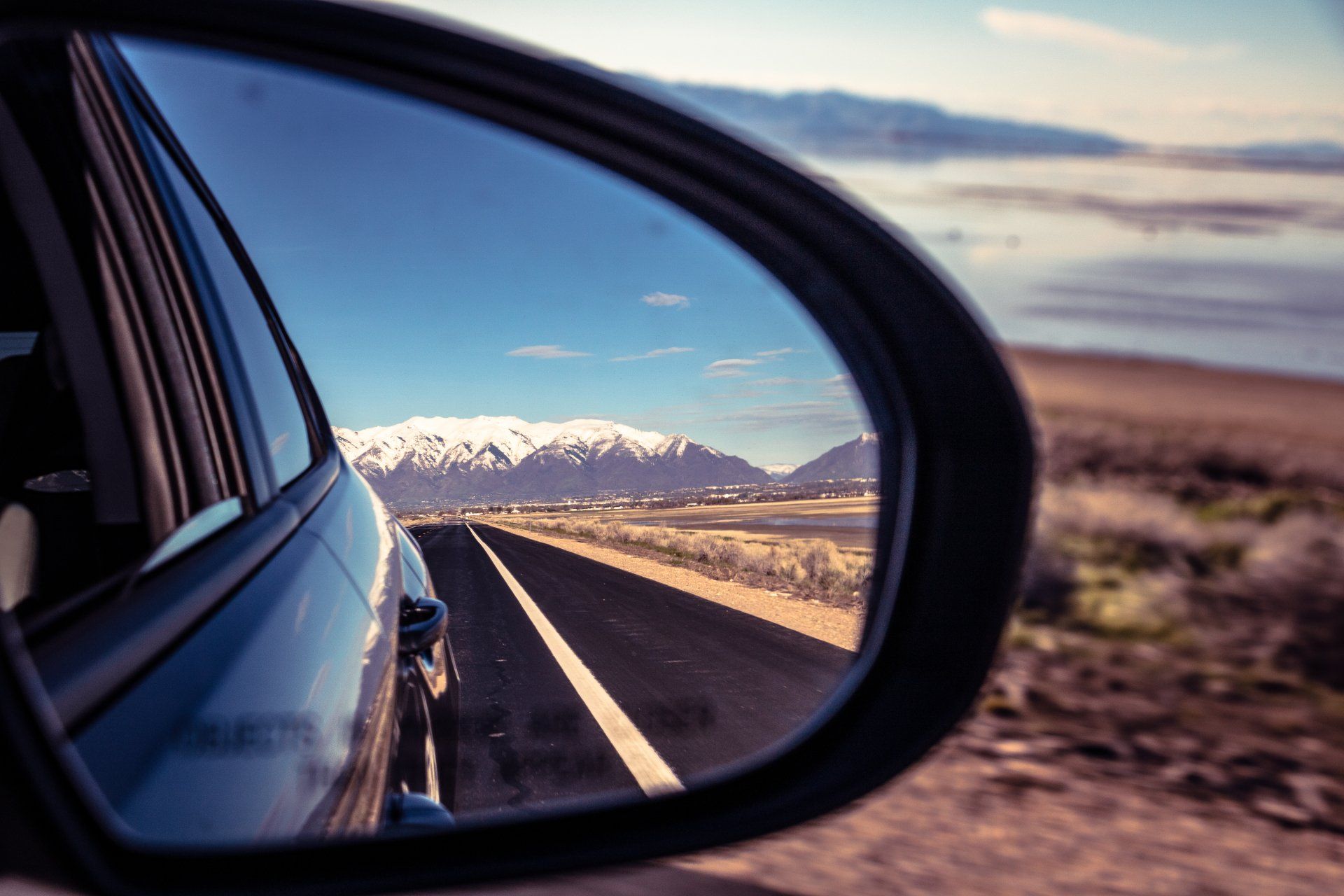 A car is driving down a road with mountains in the background
