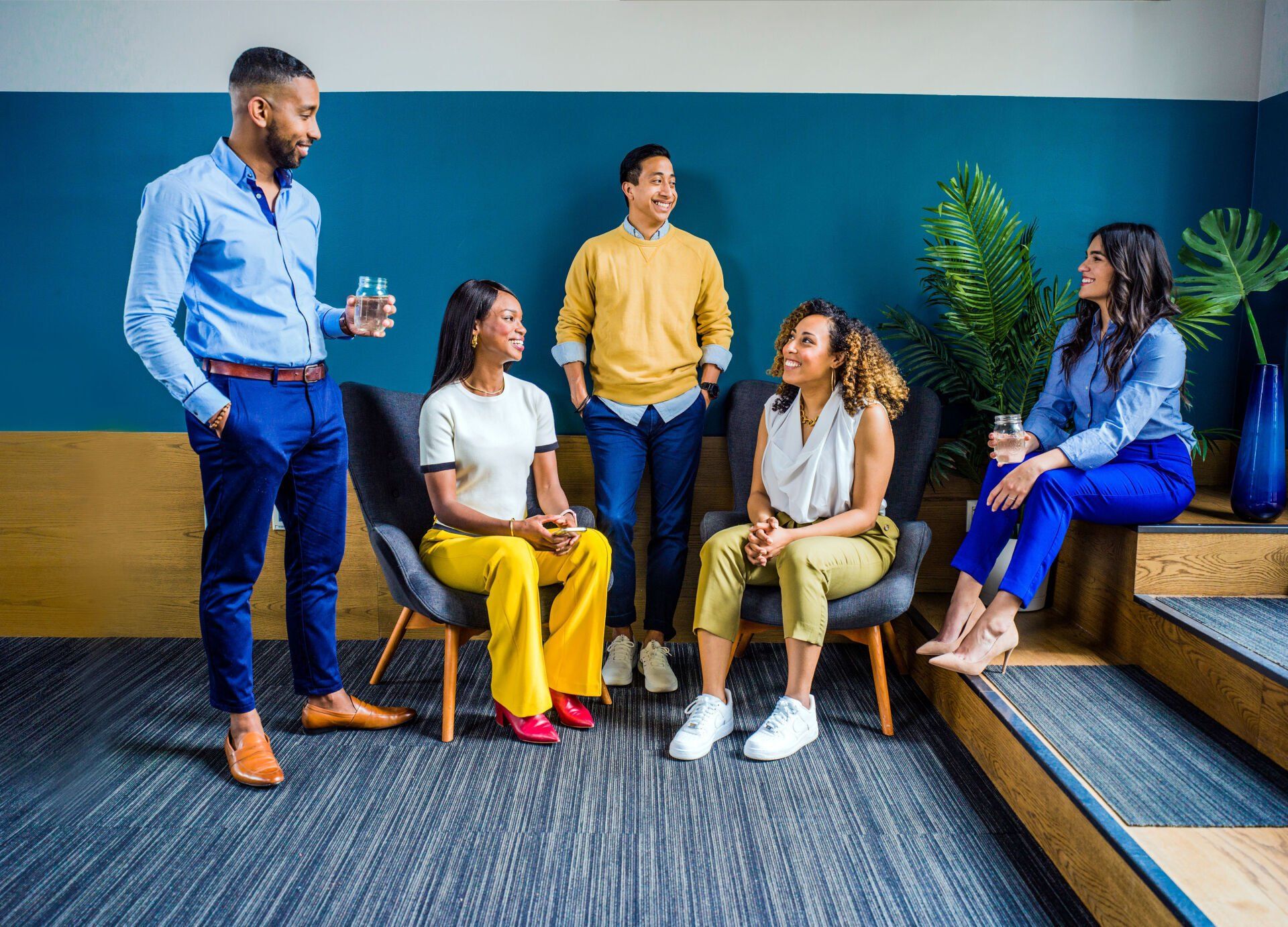 A group of people are sitting in chairs and talking to each other in a room.
