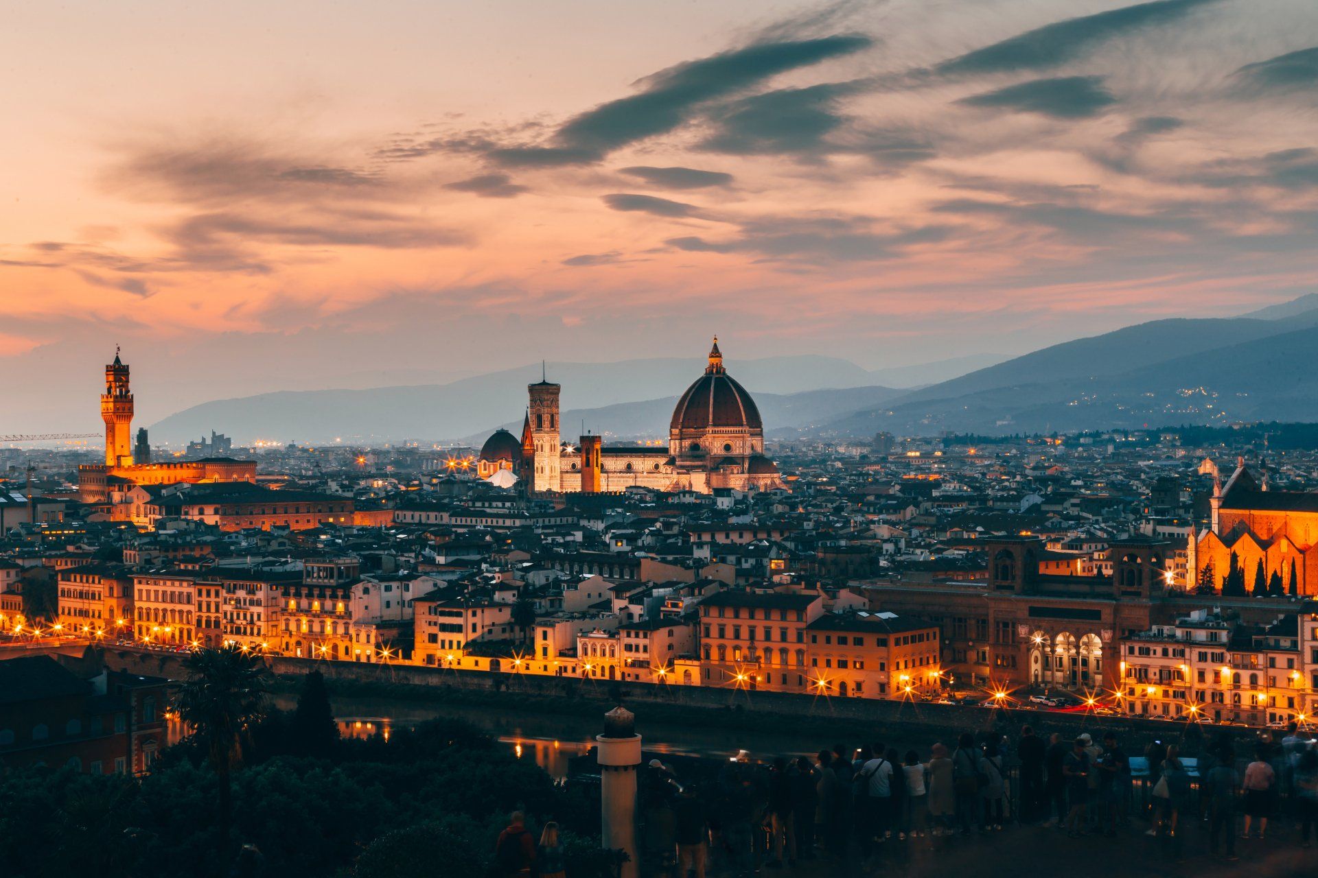 An aerial view of a city at night with a sunset in the background.