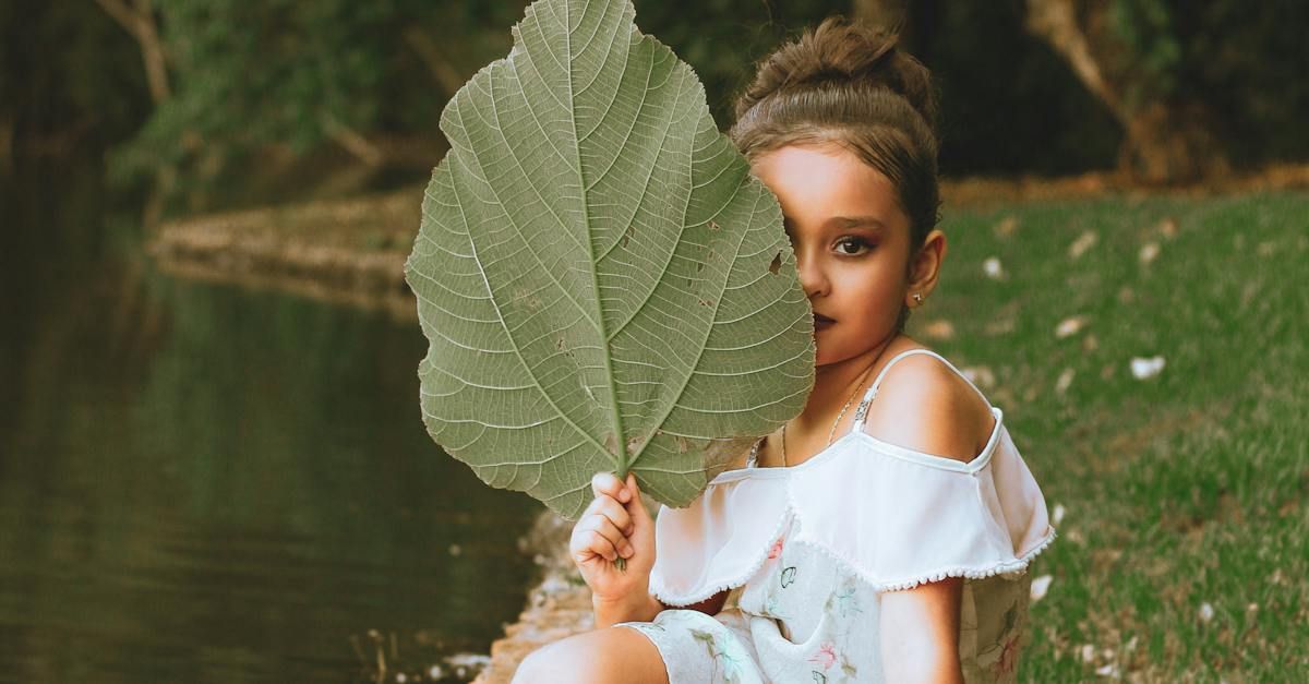 meisje verstopt zich half achter een groen blad