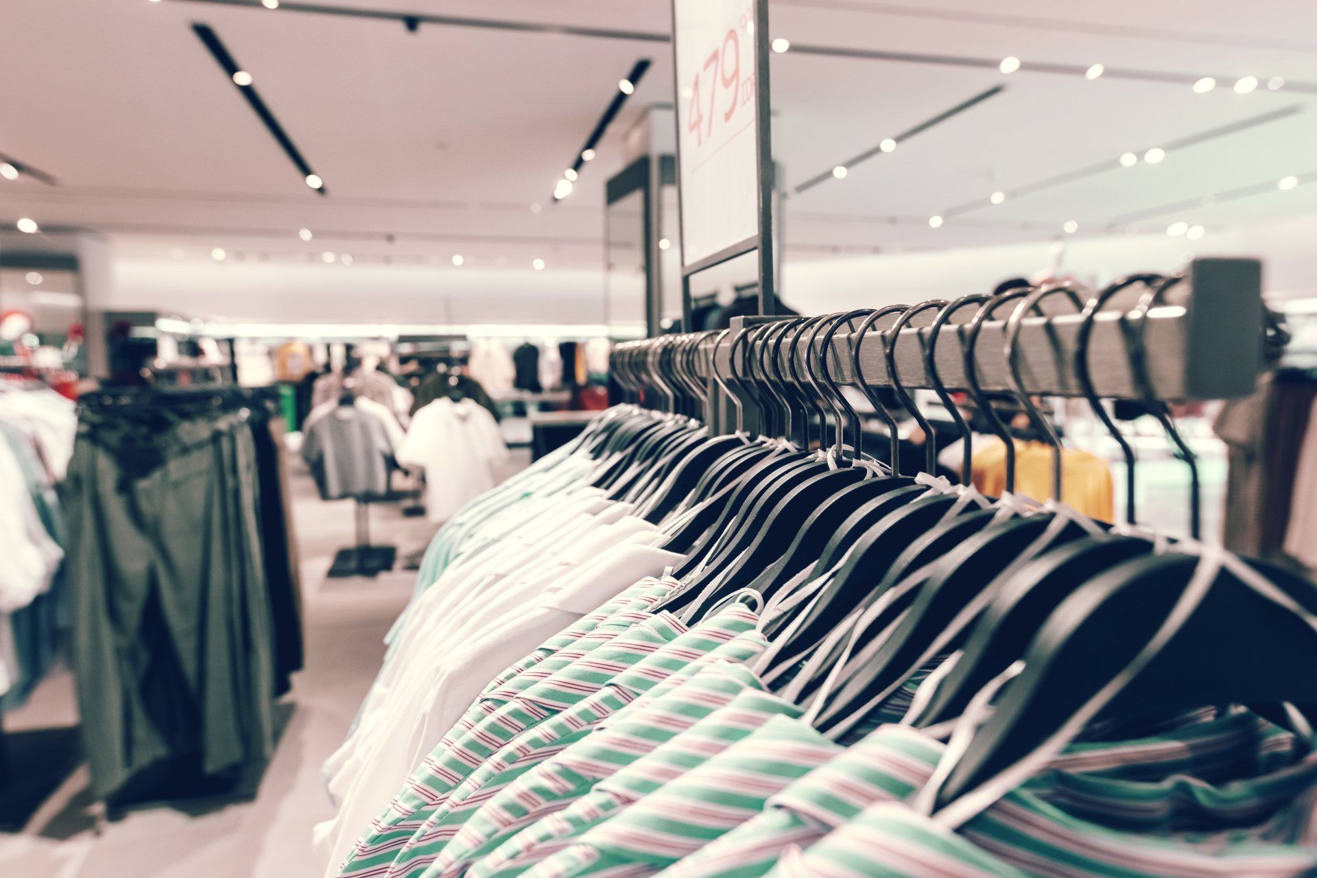 A row of clothes hanging on a rack in a clothing store.