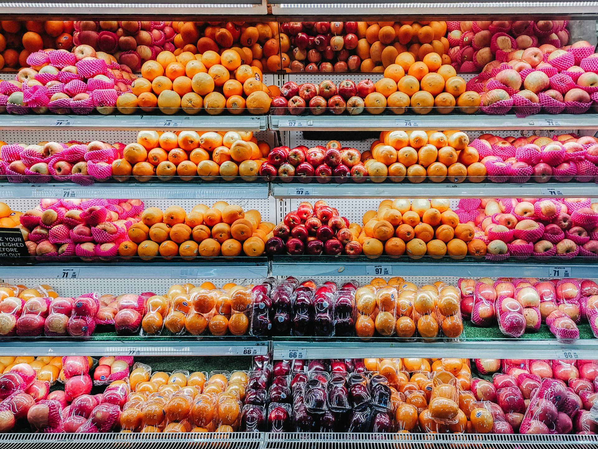 A grocery store shelf filled with lots of fruits and vegetables.