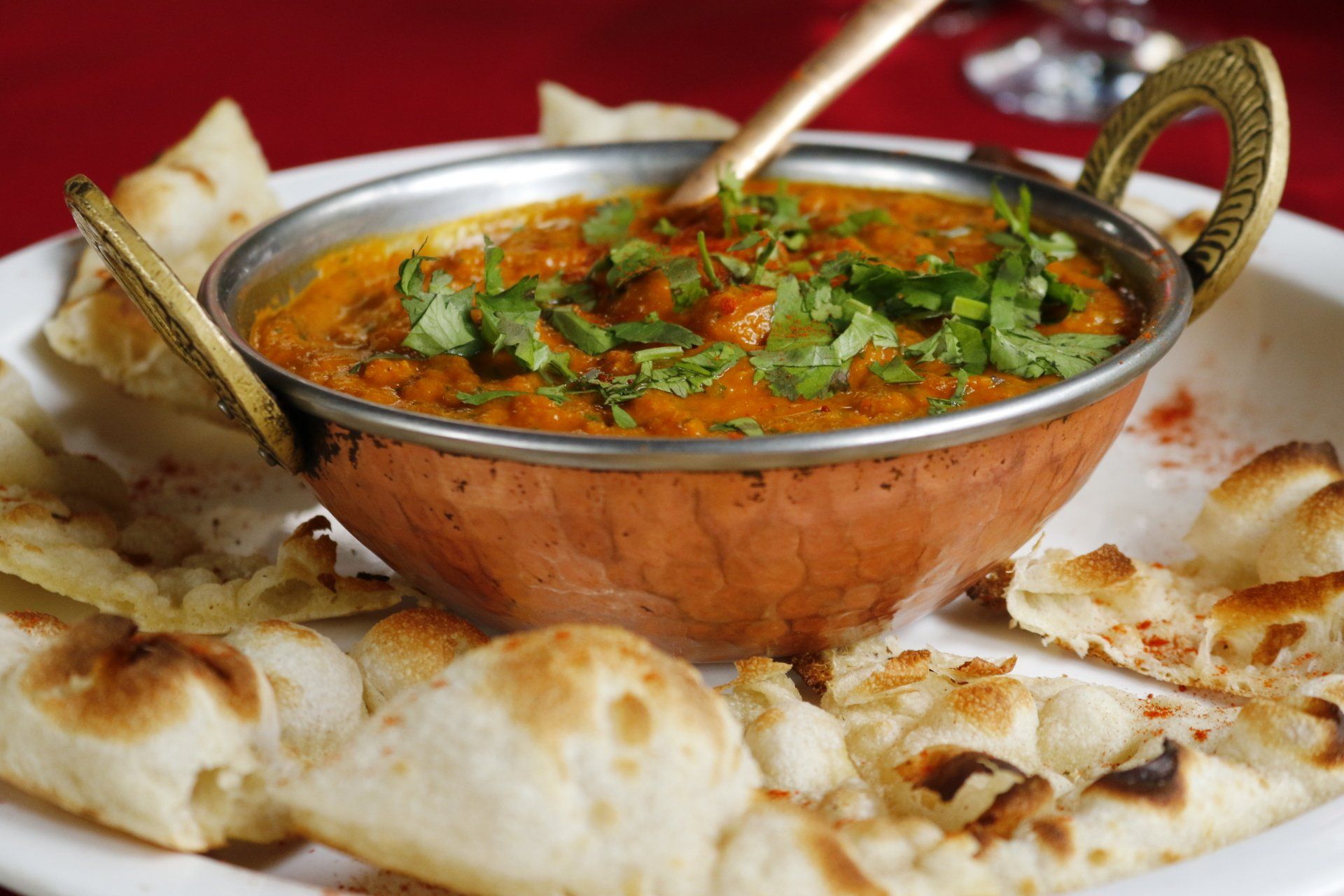 Copper bowl of curry with naan bread.