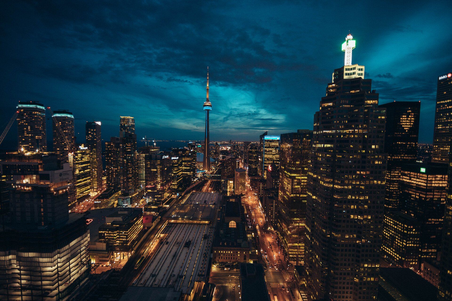 Nighttime cityscape with lit skyscrapers and CN Tower.