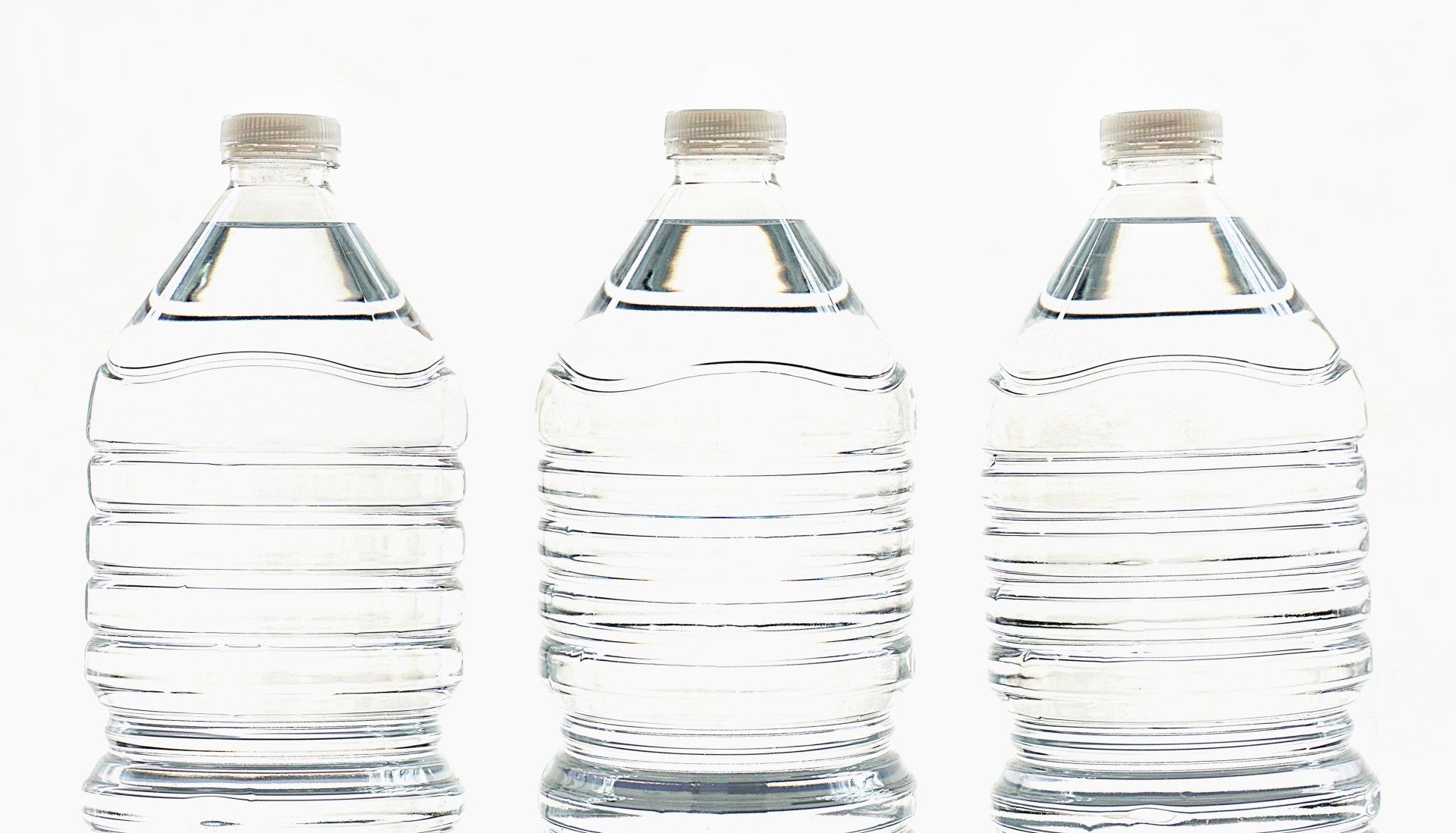Three bottles of water are lined up in a row on a white background.
