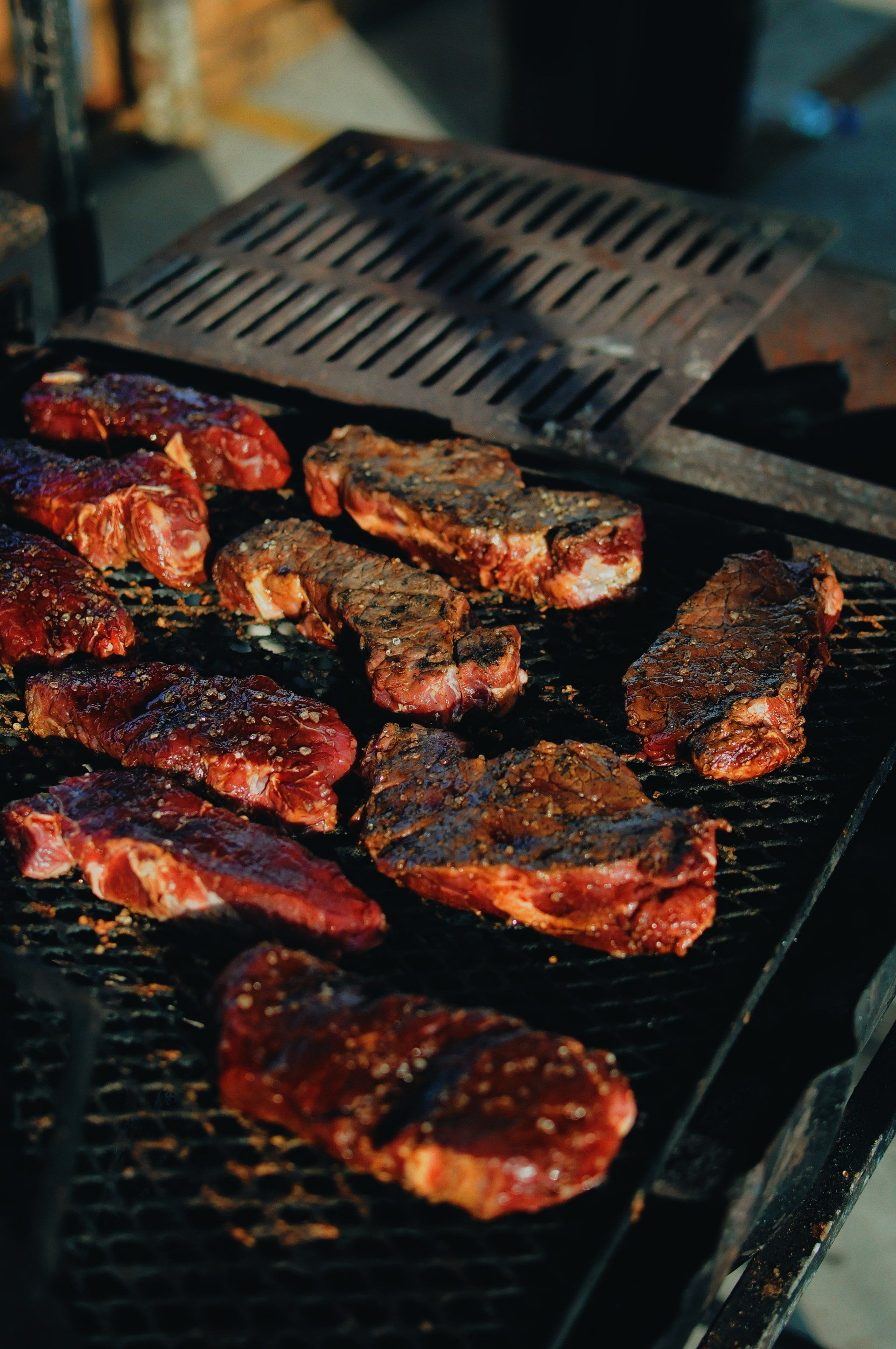 A bunch of meat is cooking on a grill.