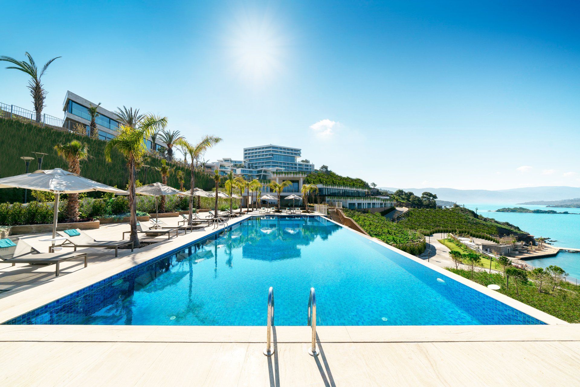 Piscina infinita de um resort de luxo com vista para o oceano sob um céu azul brilhante.