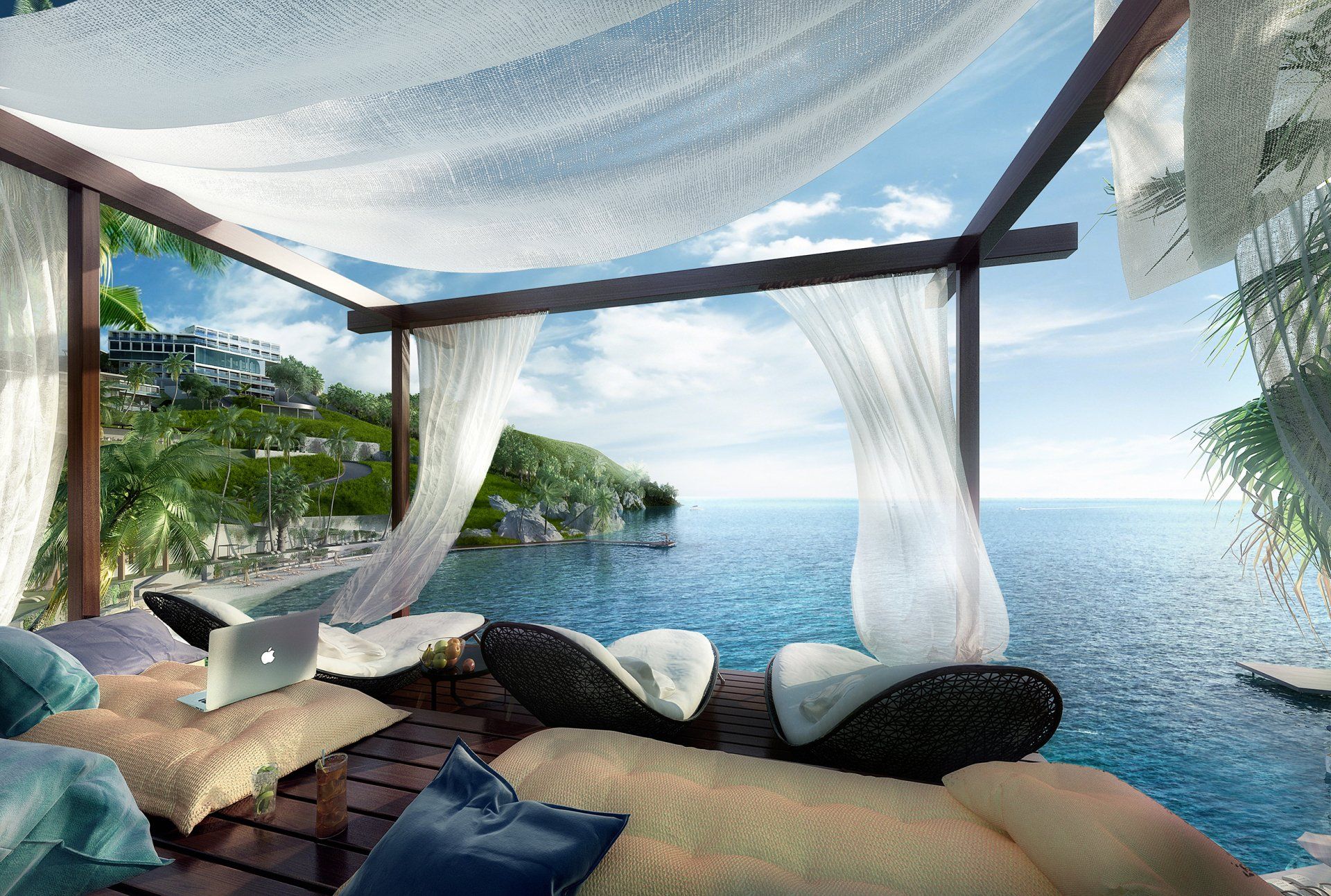Lounge ao ar livre com cortinas leves, almofadas e vista para o mar ao pôr do sol.