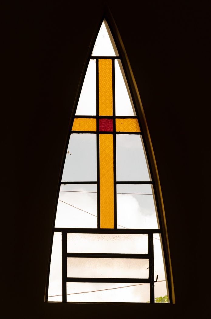 A stained glass window with a yellow cross on it