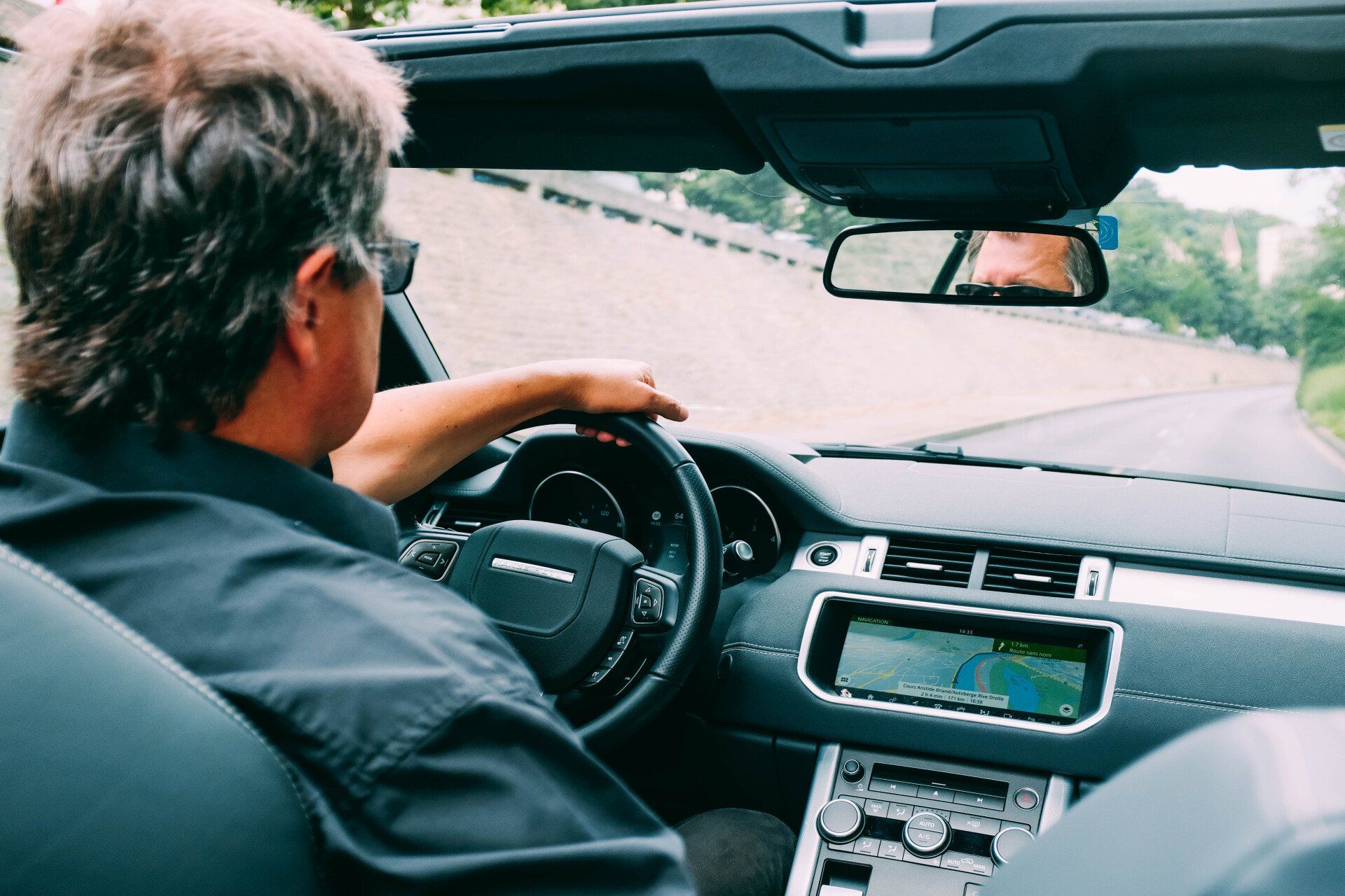 A man is driving a car down a road.