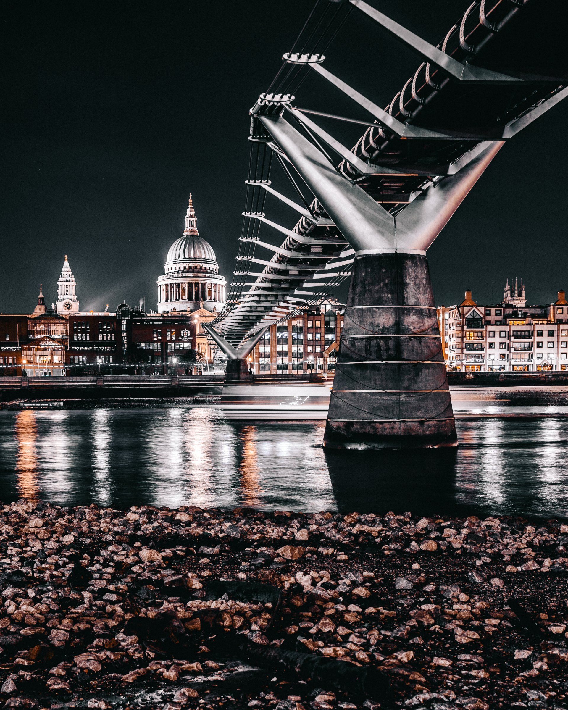 A bridge over a body of water with a city in the background at night