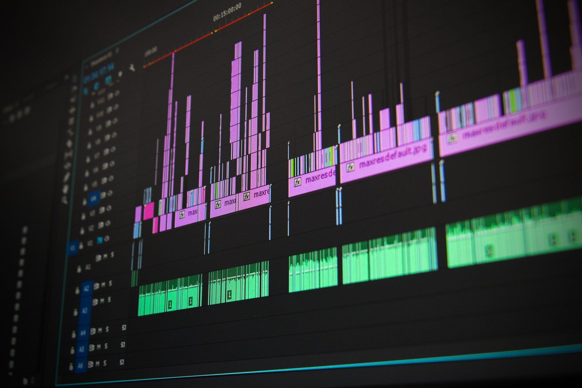 Close-up of a computer screen showing the timeline of a video editing software, with colorful audio and video tracks.