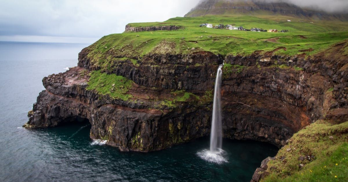 Det er en foss på siden av en klippe ved siden av havet.