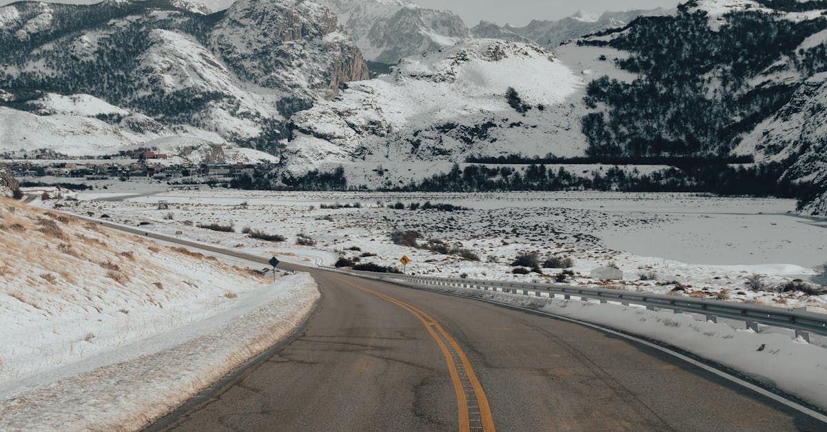 A car is driving down a snowy road in the mountains.