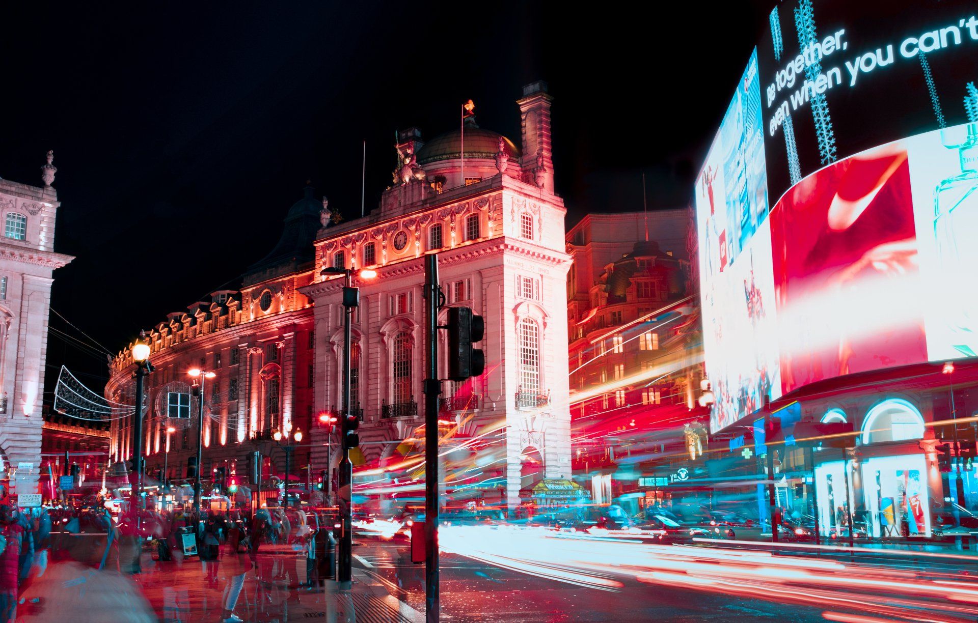 A city street at night with a large billboard that says nike on it.