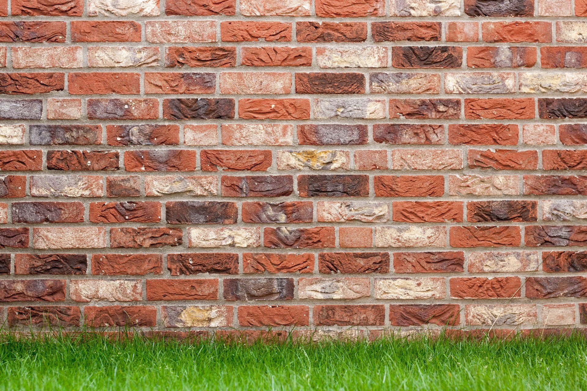 A brick wall with a patch of grass in front of it.
