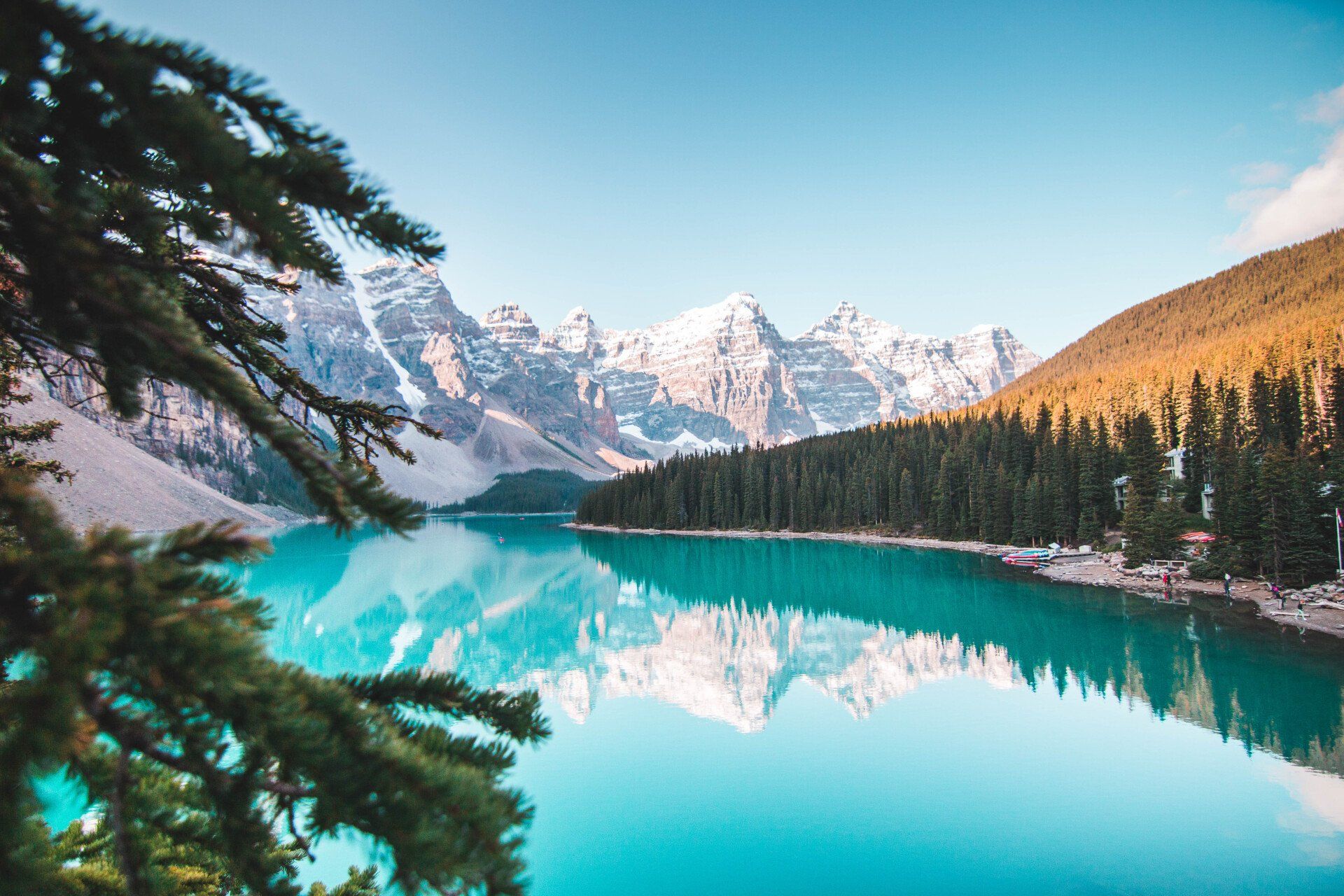 A lake surrounded by mountains and trees with a reflection of the mountains in the water.