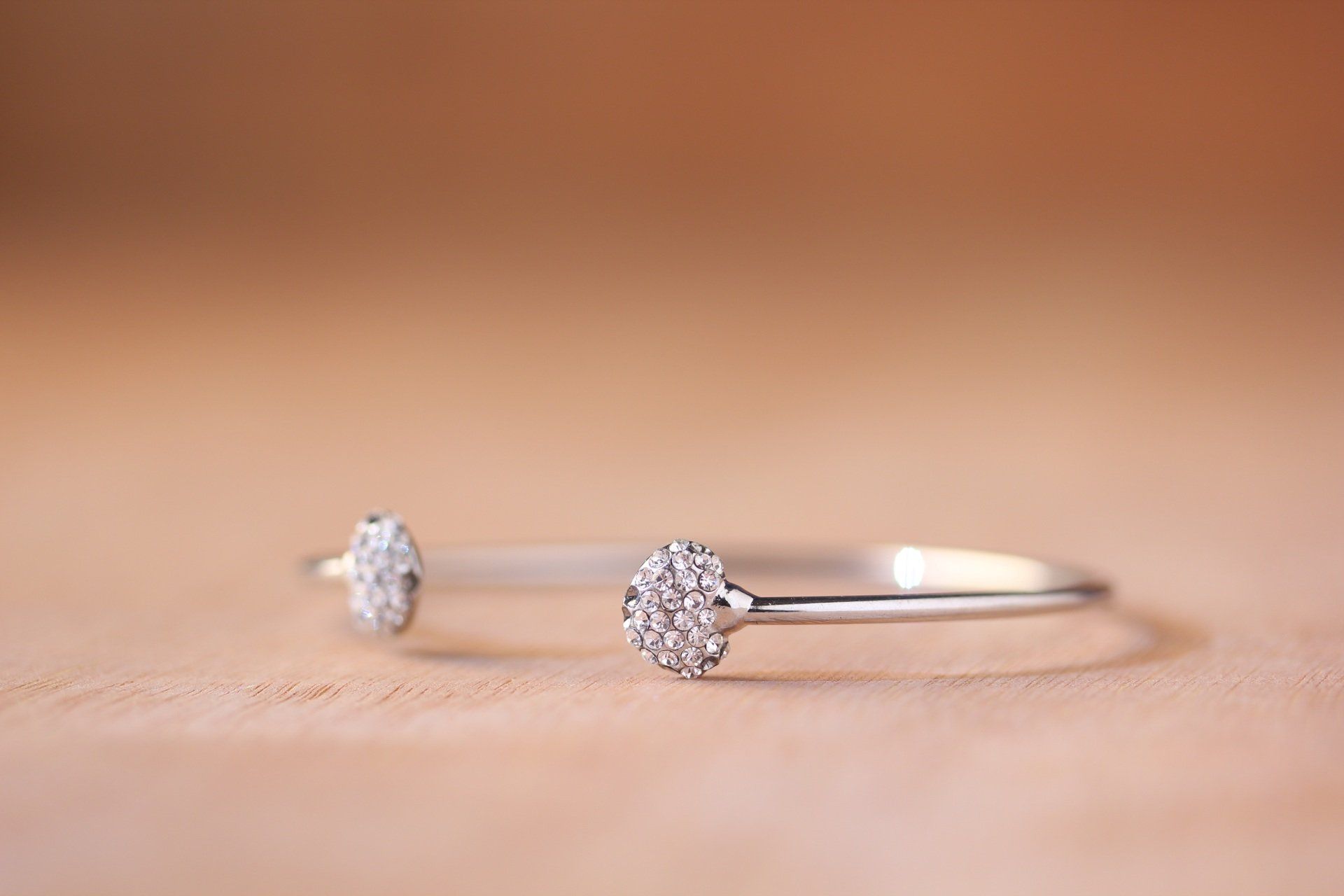 A close up of a silver bracelet with diamonds on a table.