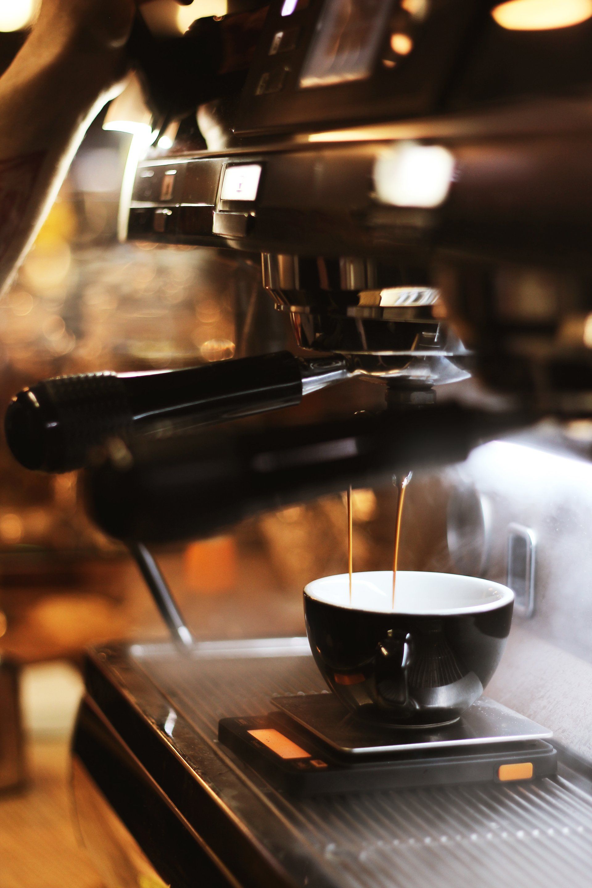 A cup of coffee is being poured from a coffee machine