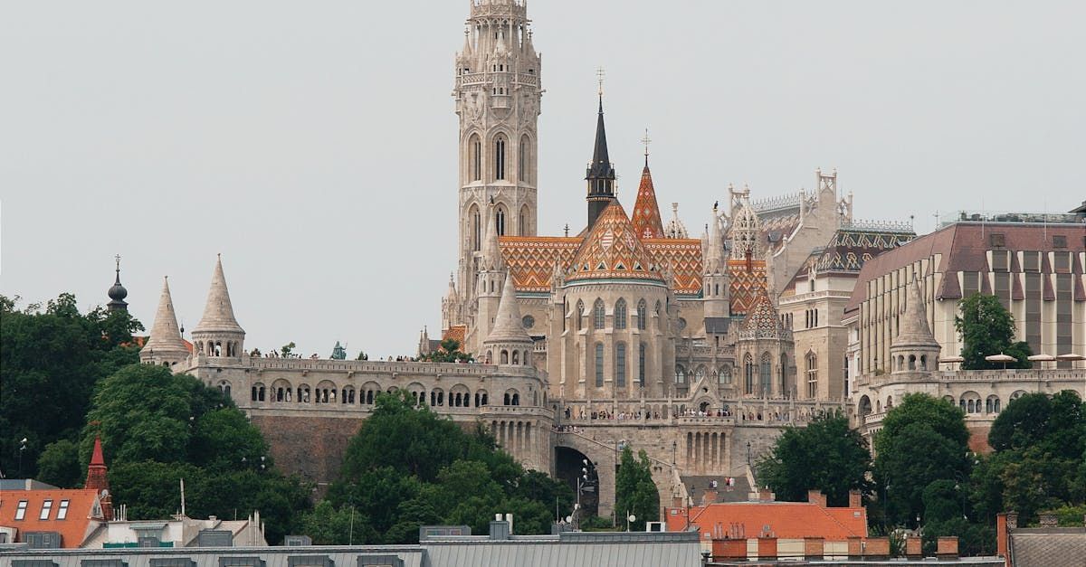 White Gothic architecture with ornate spires and tiled roof against a cloudy sky.
