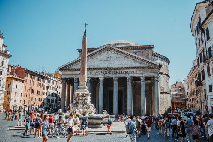 A group of people are walking in front of a large building.