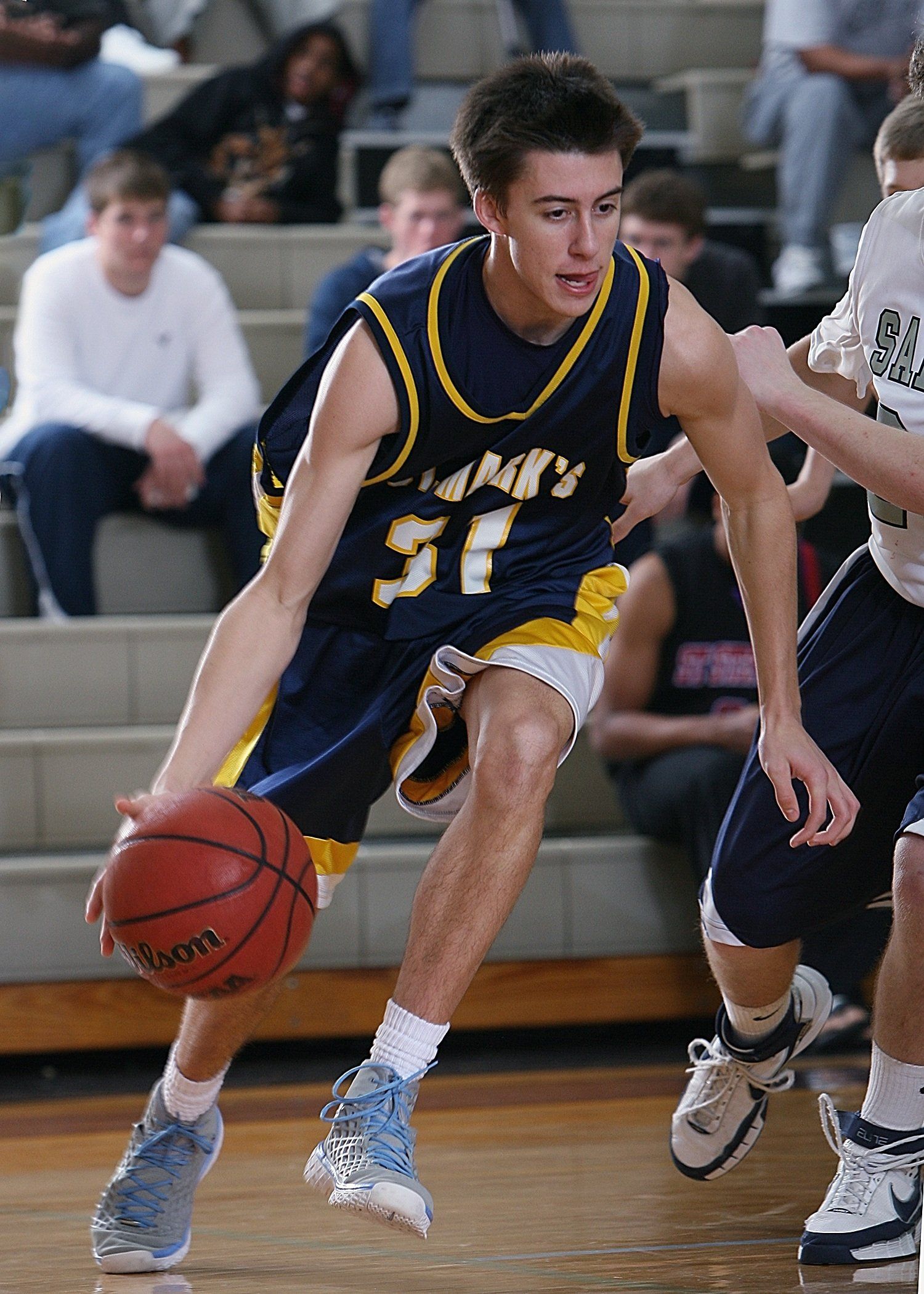 Basketball player in navy and yellow jersey dribbling during a game