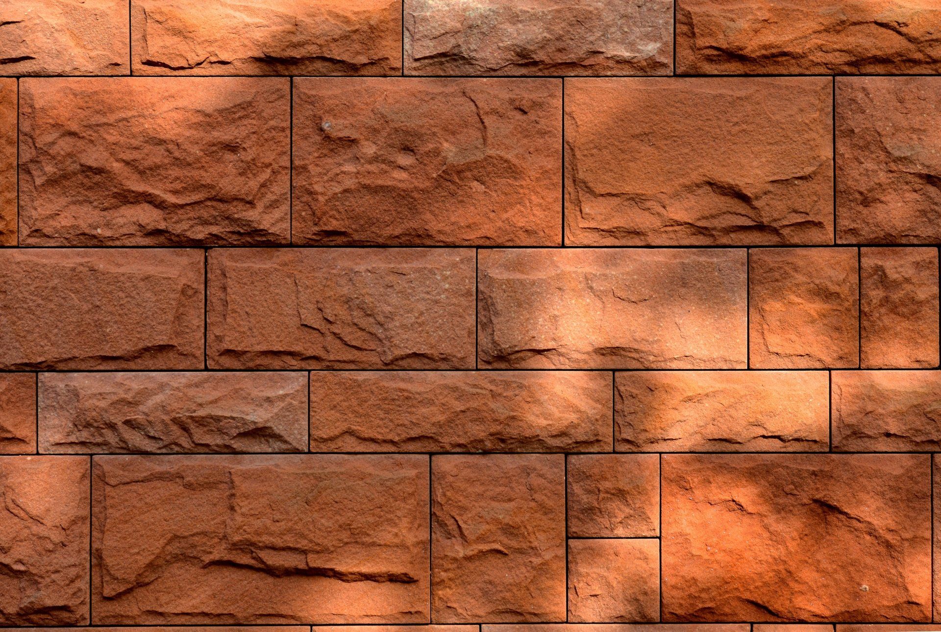 An orange colored large concrete wall with irregular shaped blocks