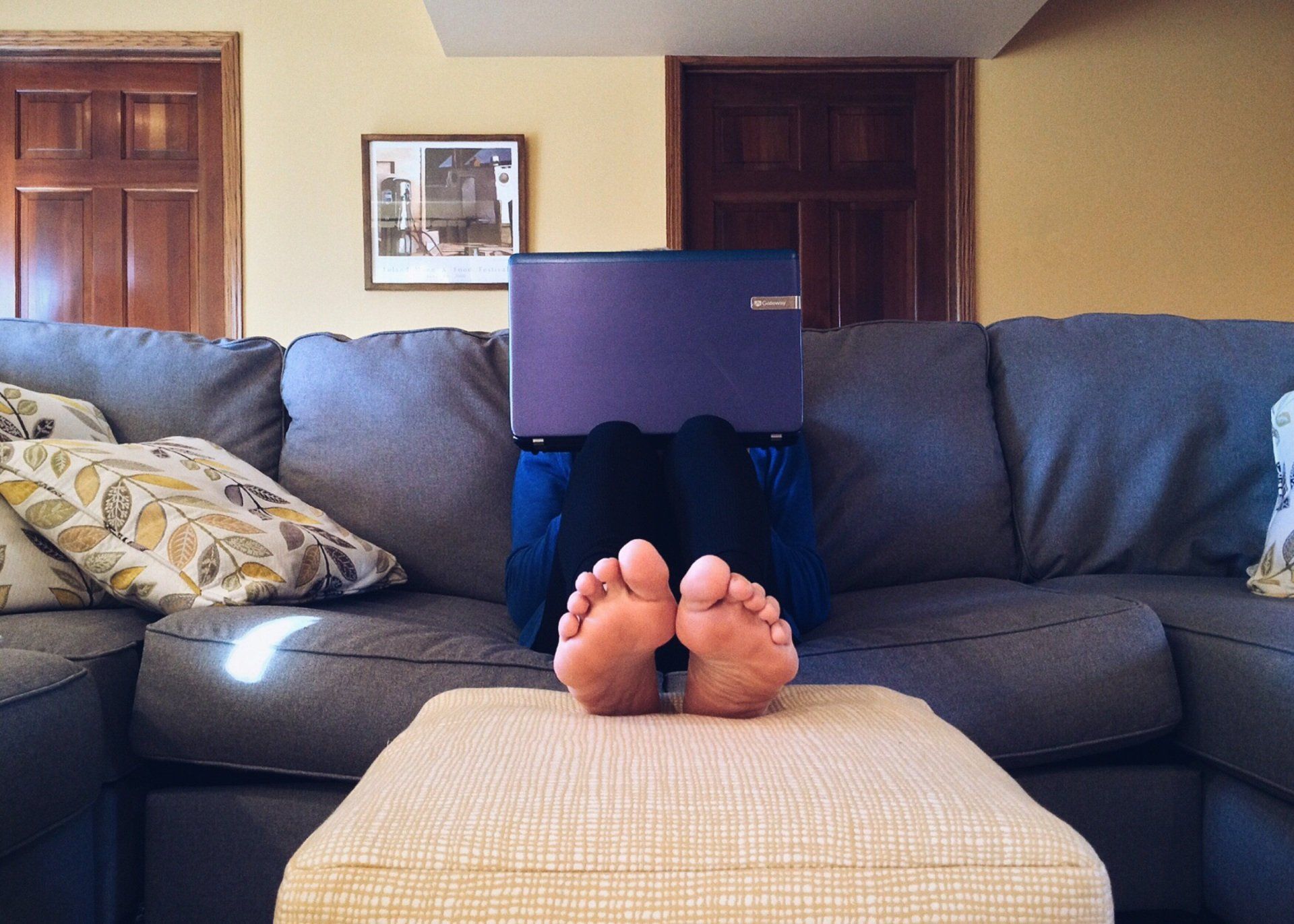 A person is laying on a couch with a laptop on their head.