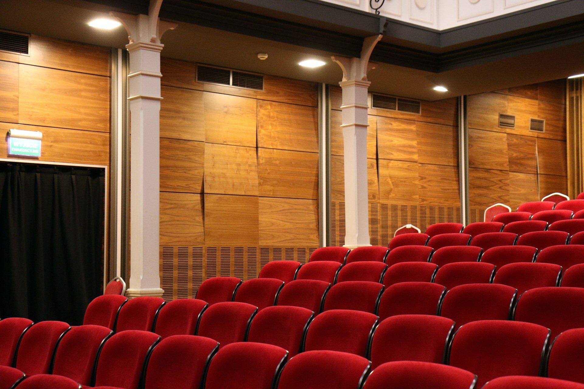 A man in a red jacket is mopping the floor of a theater.