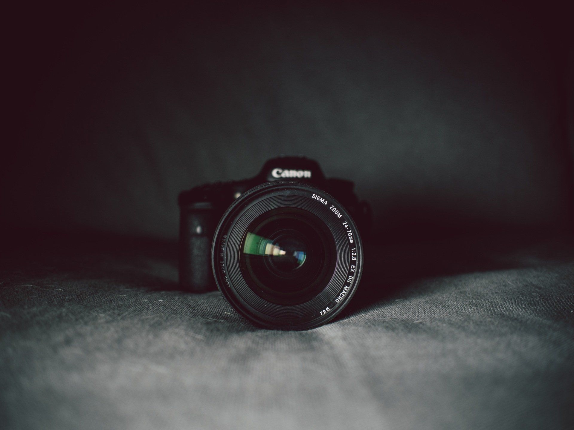A canon camera is sitting on a table in the dark.