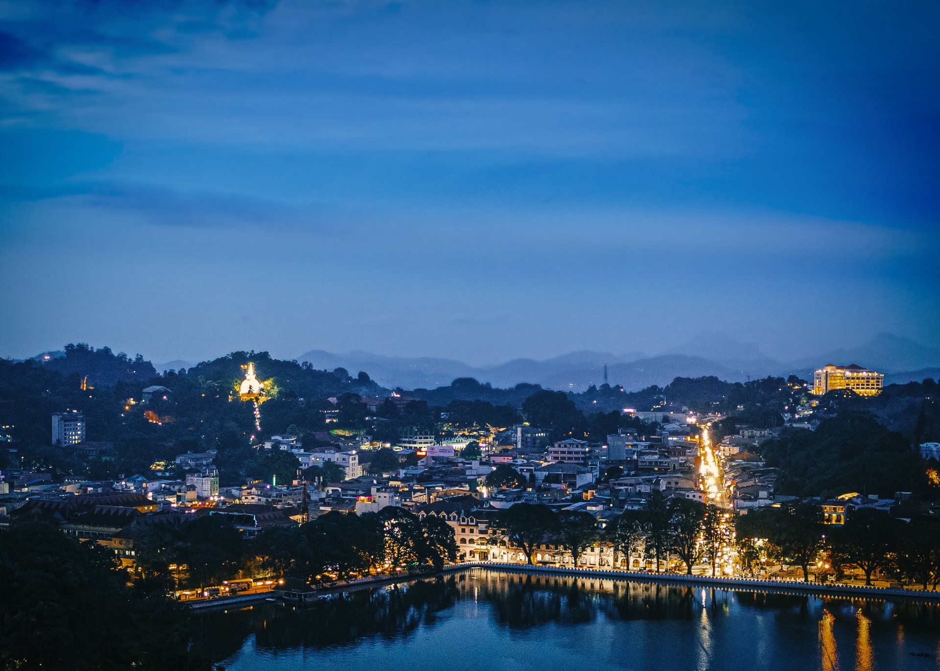 An aerial view of a city at night with a lake in the foreground.